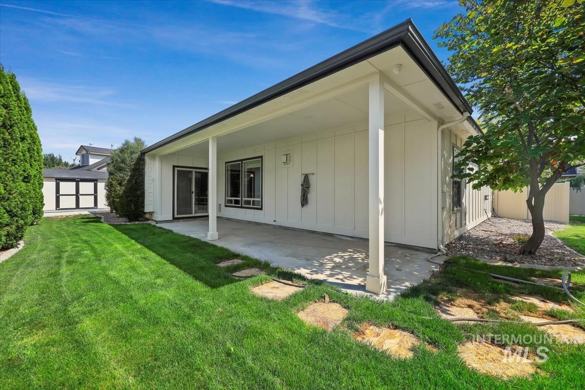 Back of house with a lawn, a patio, and board and batten siding