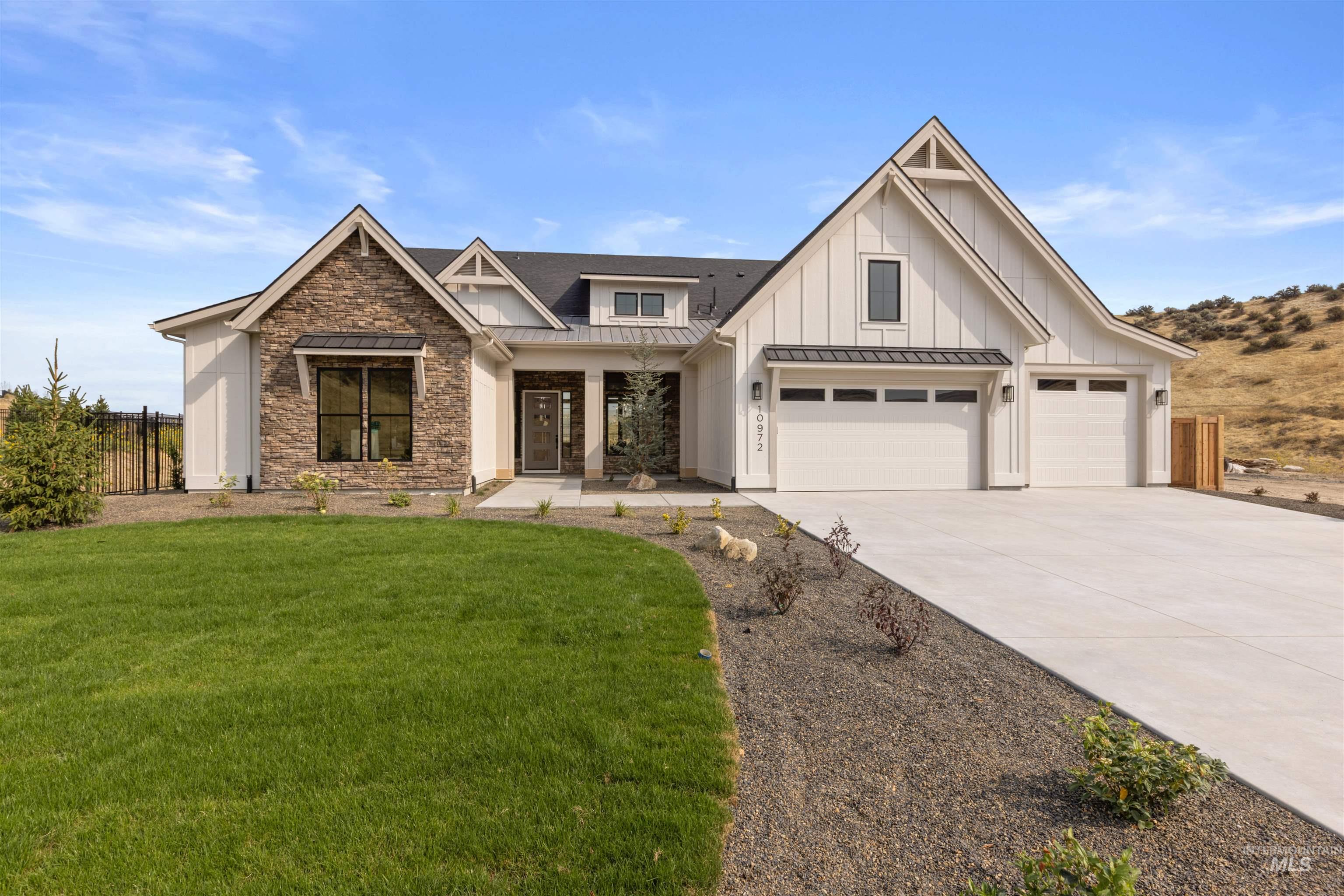 Modern inspired farmhouse with a standing seam roof, a metal roof, covered porch, board and batten siding, and stone siding