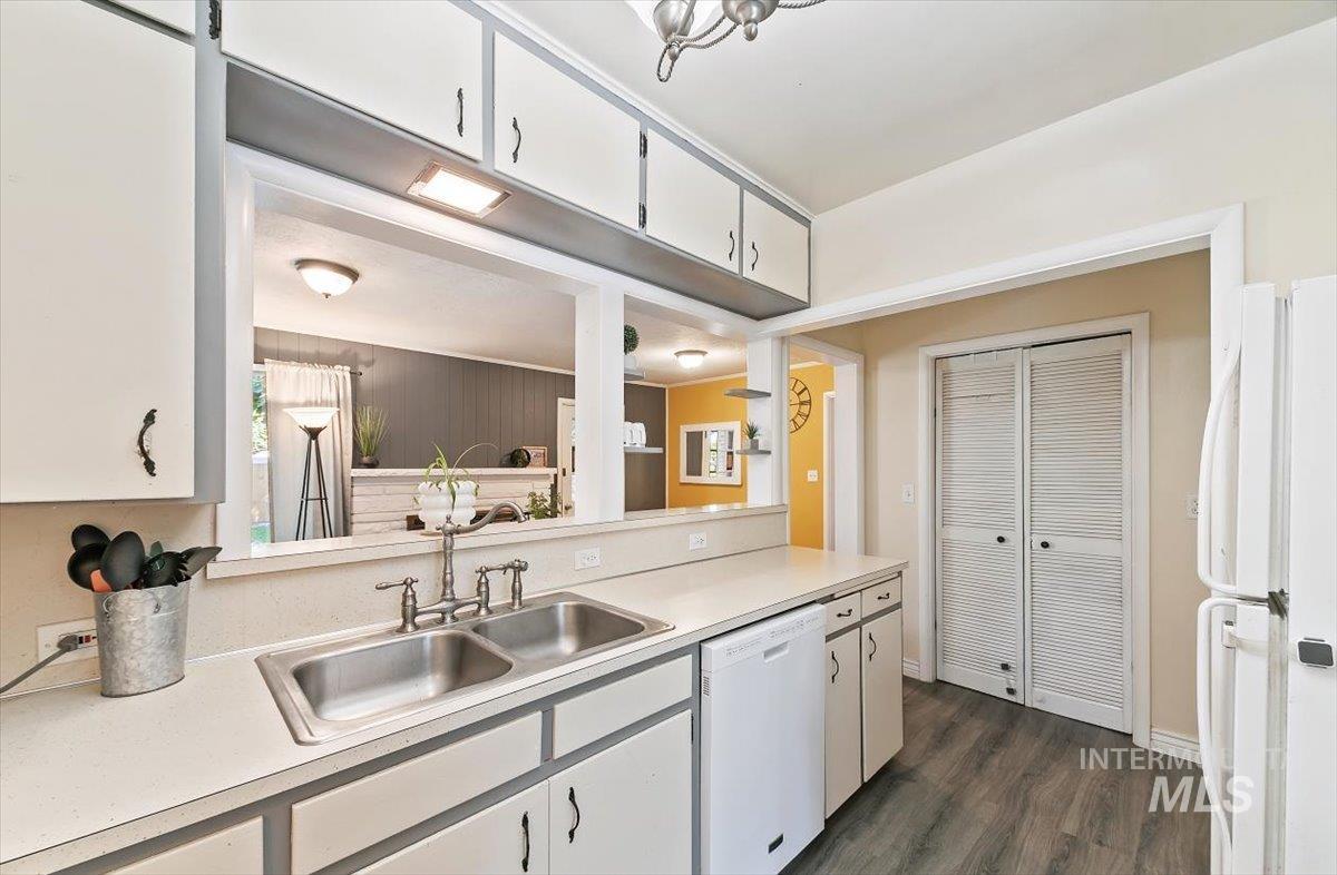 Kitchen featuring white appliances, light countertops, dark wood-type flooring, and white cabinetry