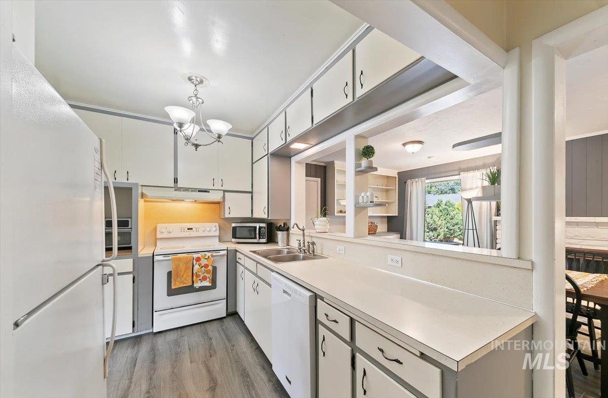 Kitchen featuring white appliances, light countertops, light wood-style flooring, and under cabinet range hood