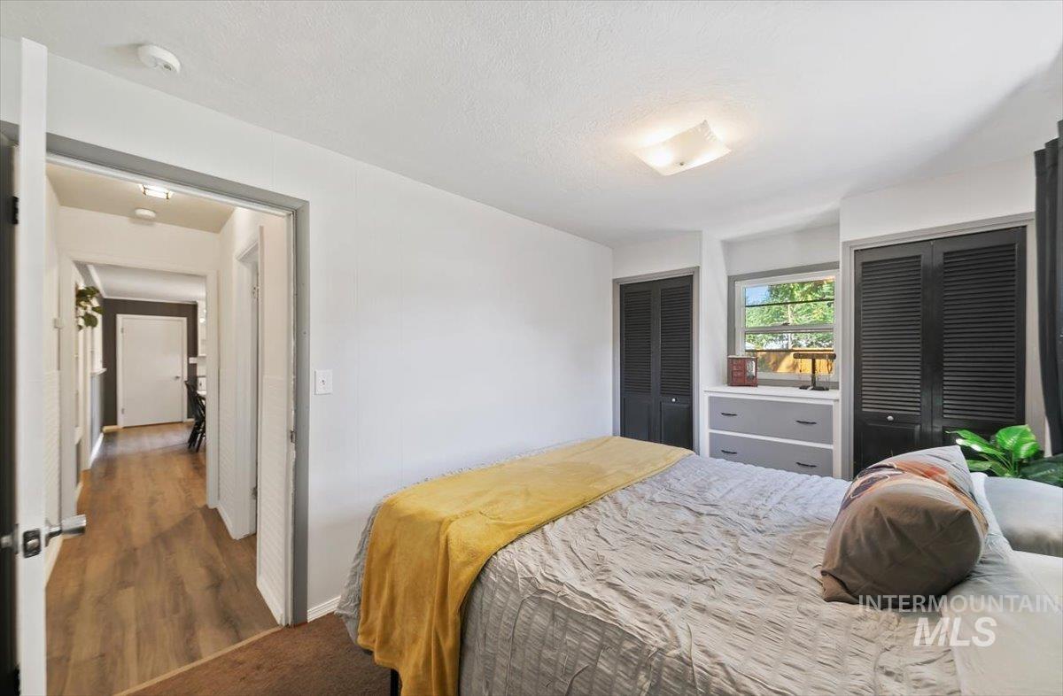 Bedroom featuring two closets, wood finished floors, and a textured ceiling