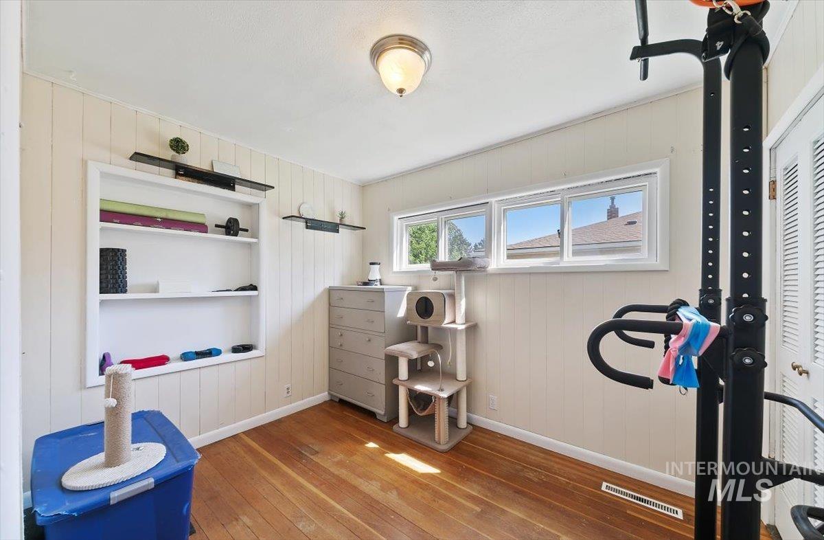Exercise room with wood walls, light wood-style floors, and built in shelves