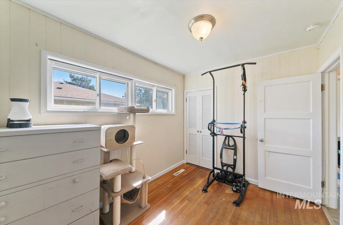 Exercise area featuring light wood finished floors, wooden walls, and ornamental molding