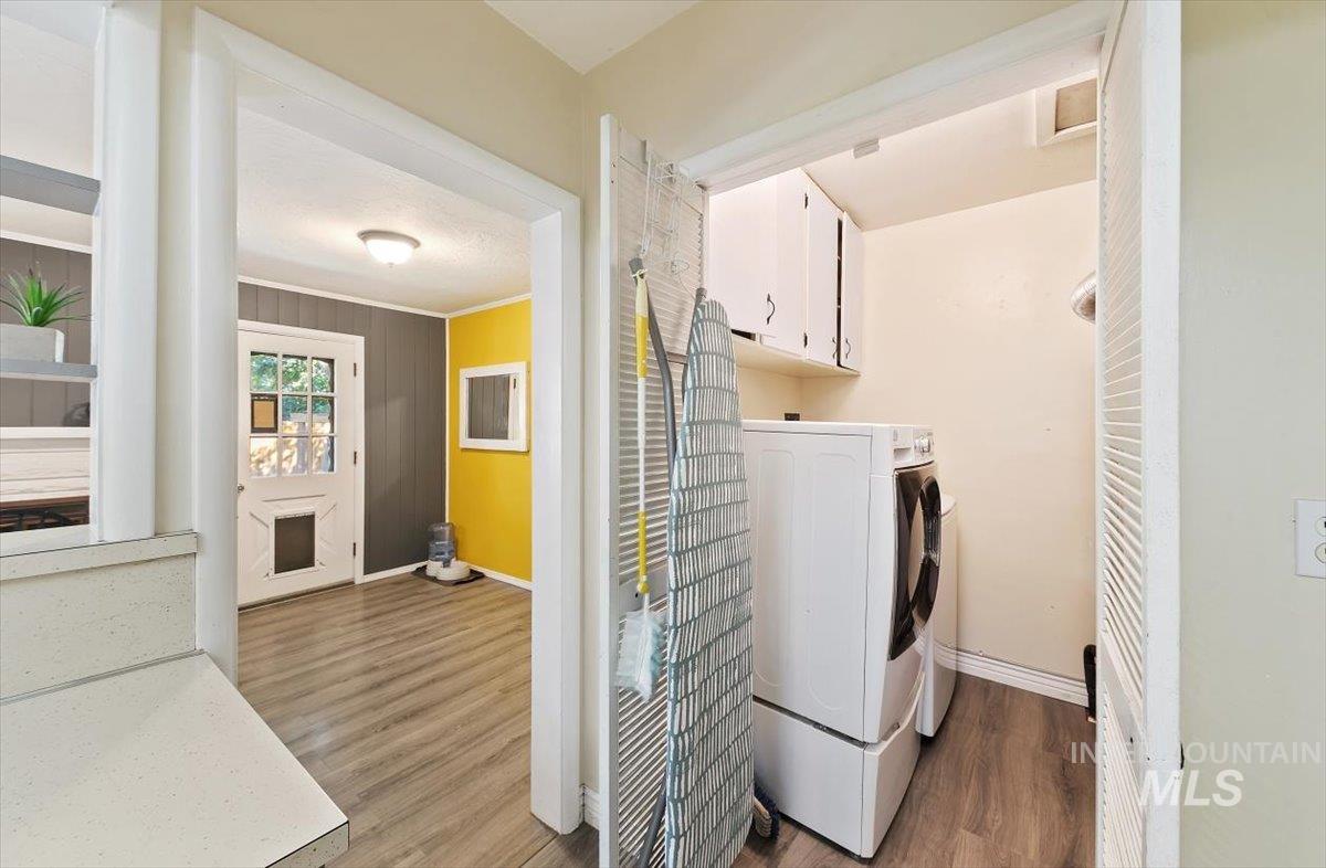 Laundry room featuring dark wood-style flooring, cabinet space, crown molding, independent washer and dryer, and a textured ceiling
