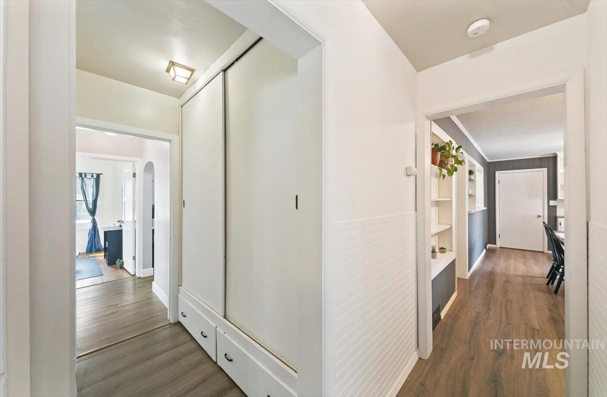 Hall with dark wood finished floors, arched walkways, and built in shelves