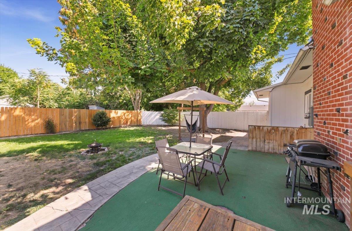 Fenced backyard featuring a patio area, a grill, a fire pit, and outdoor dining area