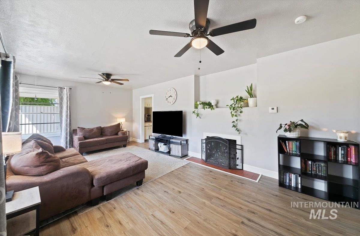 Living room featuring light wood-style flooring, a ceiling fan, and a textured ceiling