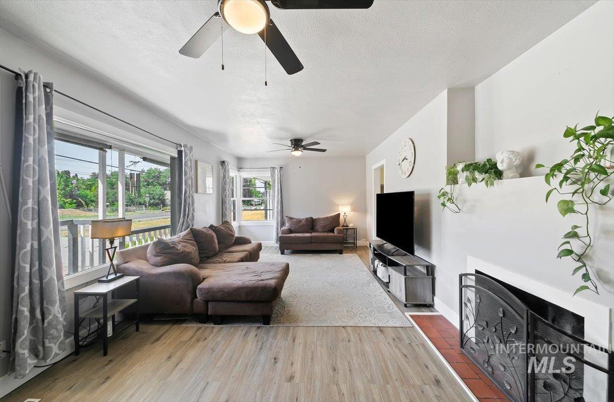 Living area with a fireplace, light wood-style floors, and a textured ceiling