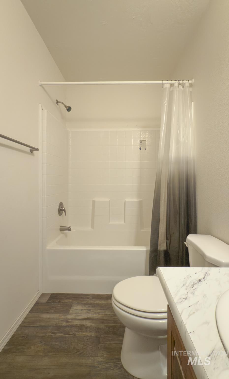Bathroom with shower / bath combo with shower curtain, dark wood-type flooring, and vanity