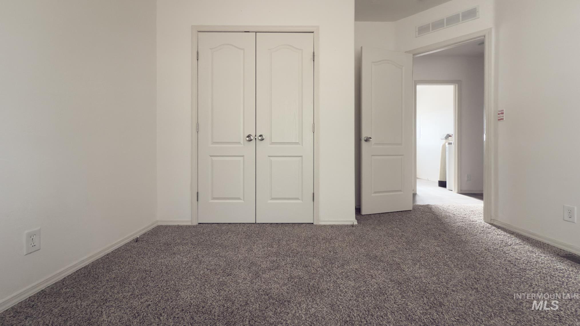 Unfurnished bedroom featuring dark colored carpet and a closet