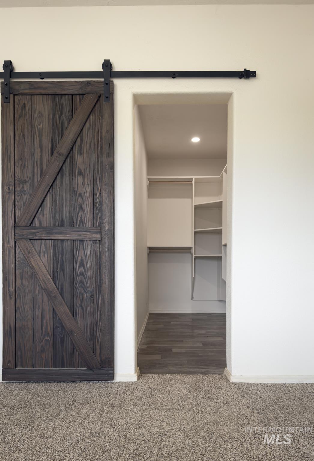 Spacious closet featuring dark colored carpet