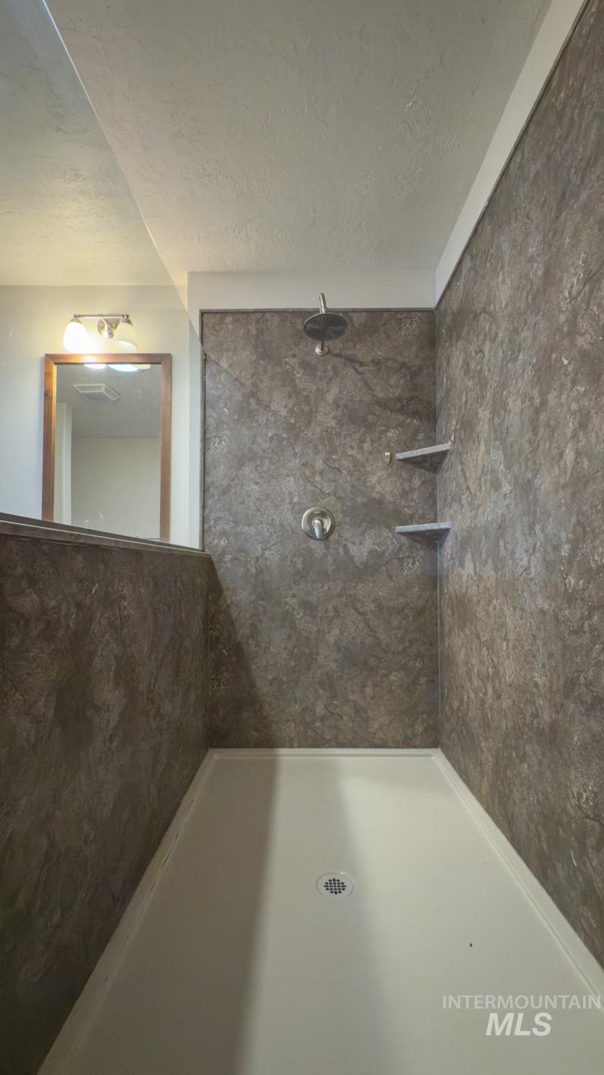 Bathroom with a textured ceiling and tiled shower