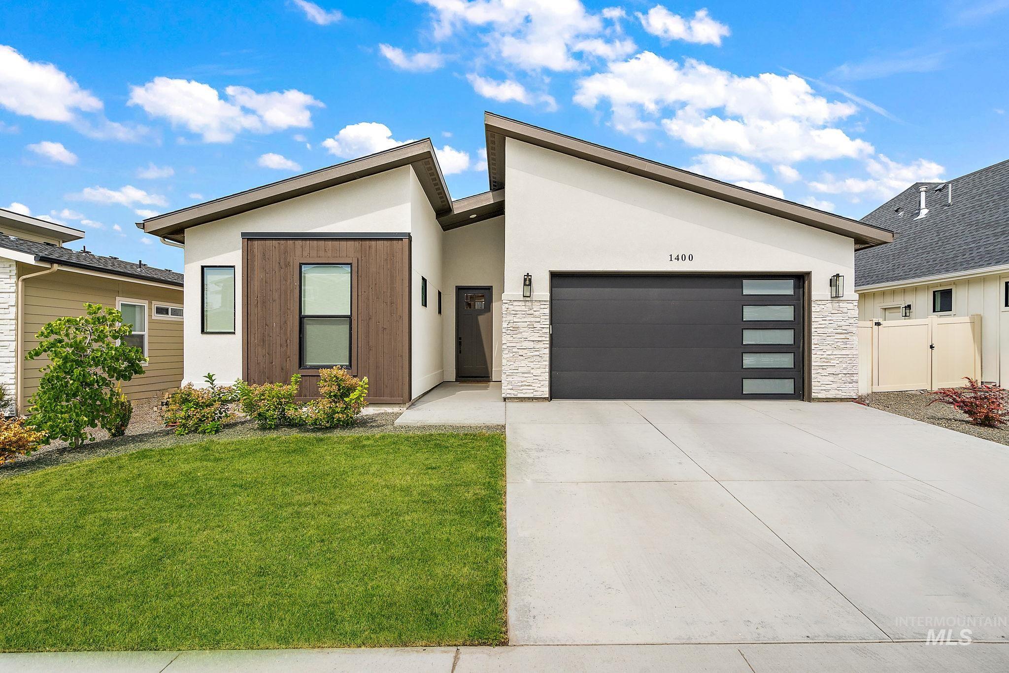 Contemporary home with stone siding, driveway, stucco siding, and an attached garage