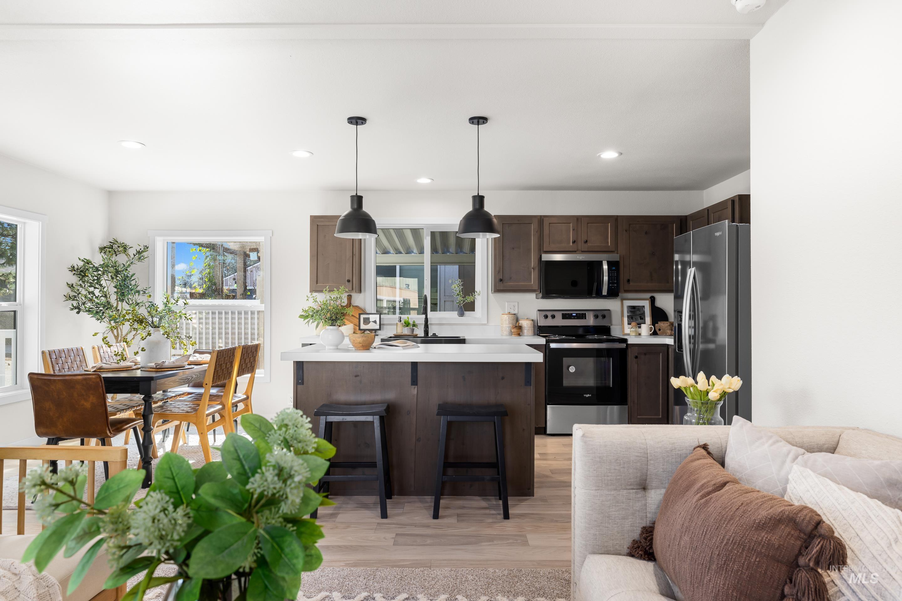 Kitchen featuring a breakfast bar area, light countertops, a peninsula, appliances with stainless steel finishes, and light wood finished floors