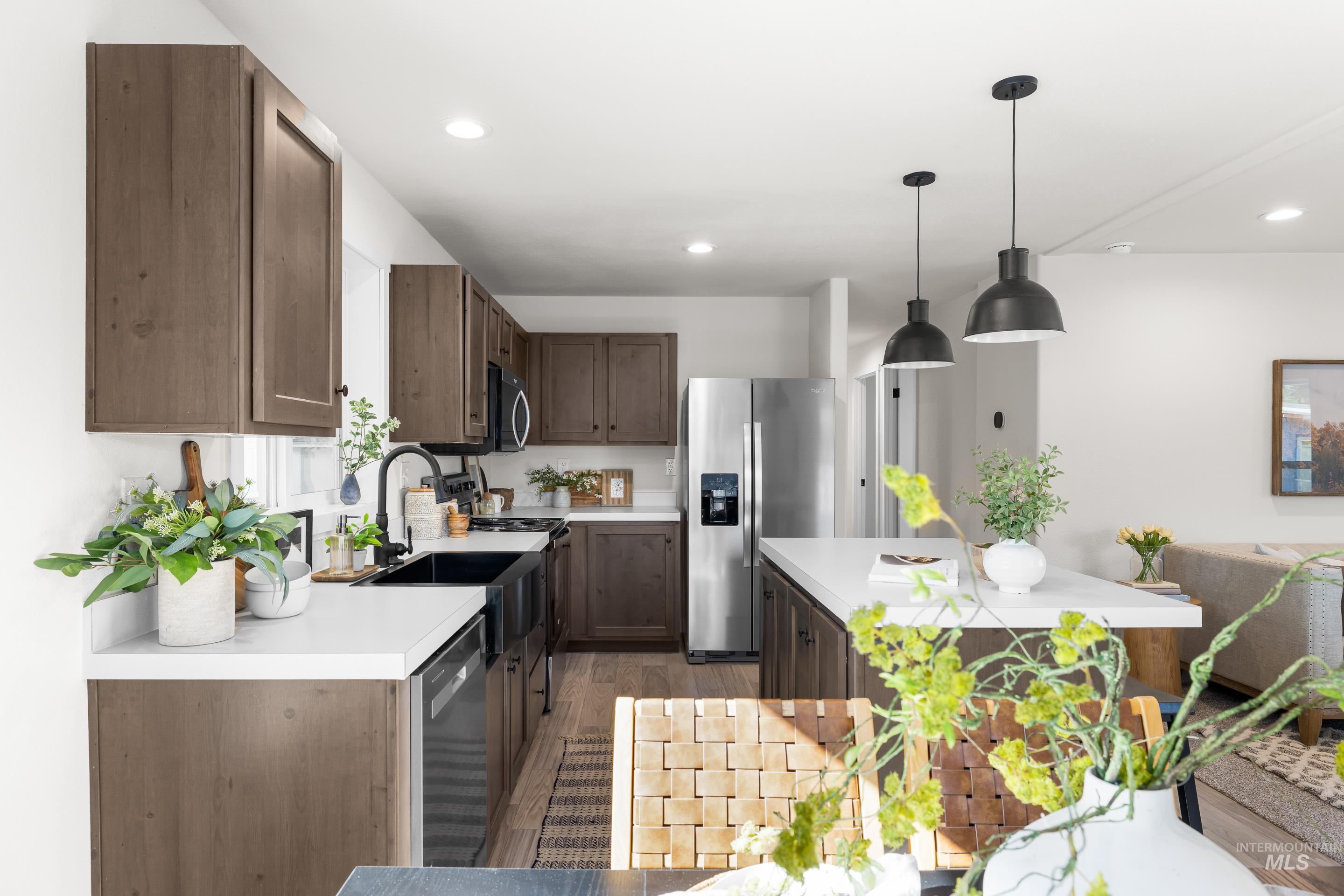 Kitchen featuring stainless steel appliances, light wood-style floors, light countertops, hanging light fixtures, and recessed lighting