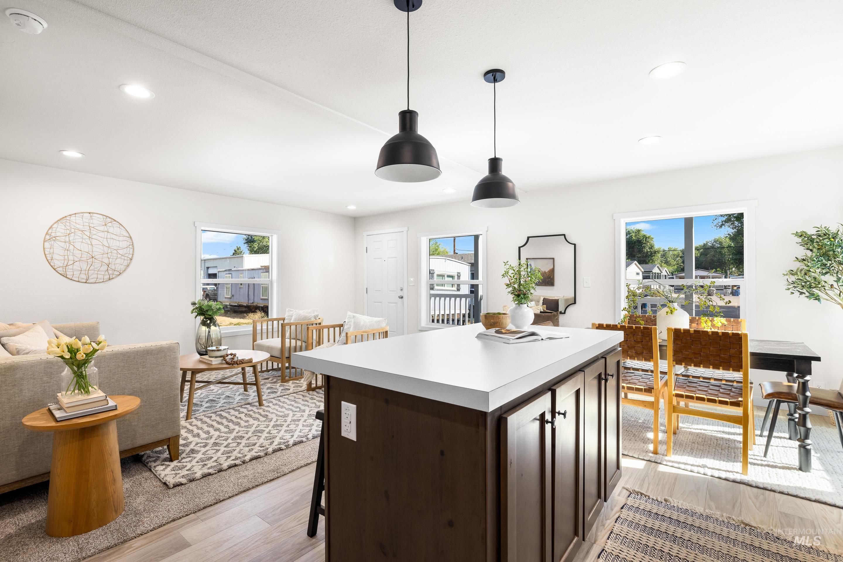 Kitchen featuring dark brown cabinets, light countertops, light wood-type flooring, recessed lighting, and hanging light fixtures