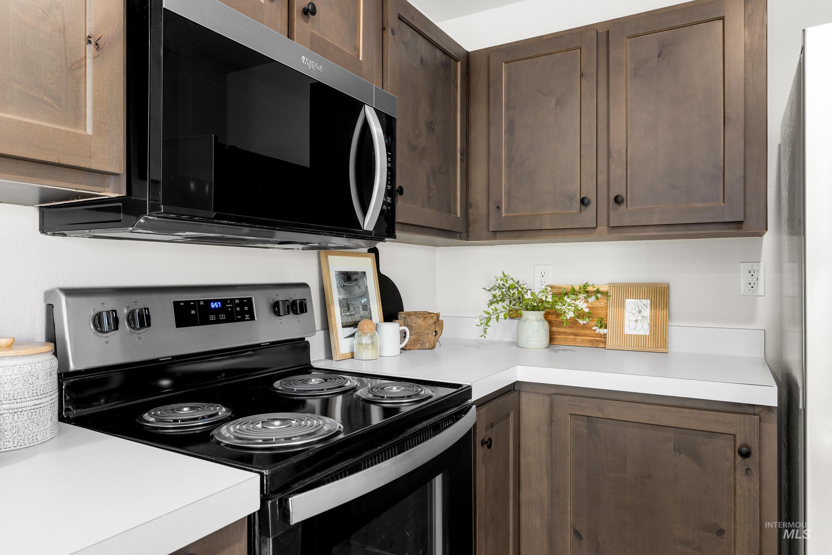 Kitchen with appliances with stainless steel finishes, light countertops, and dark brown cabinets