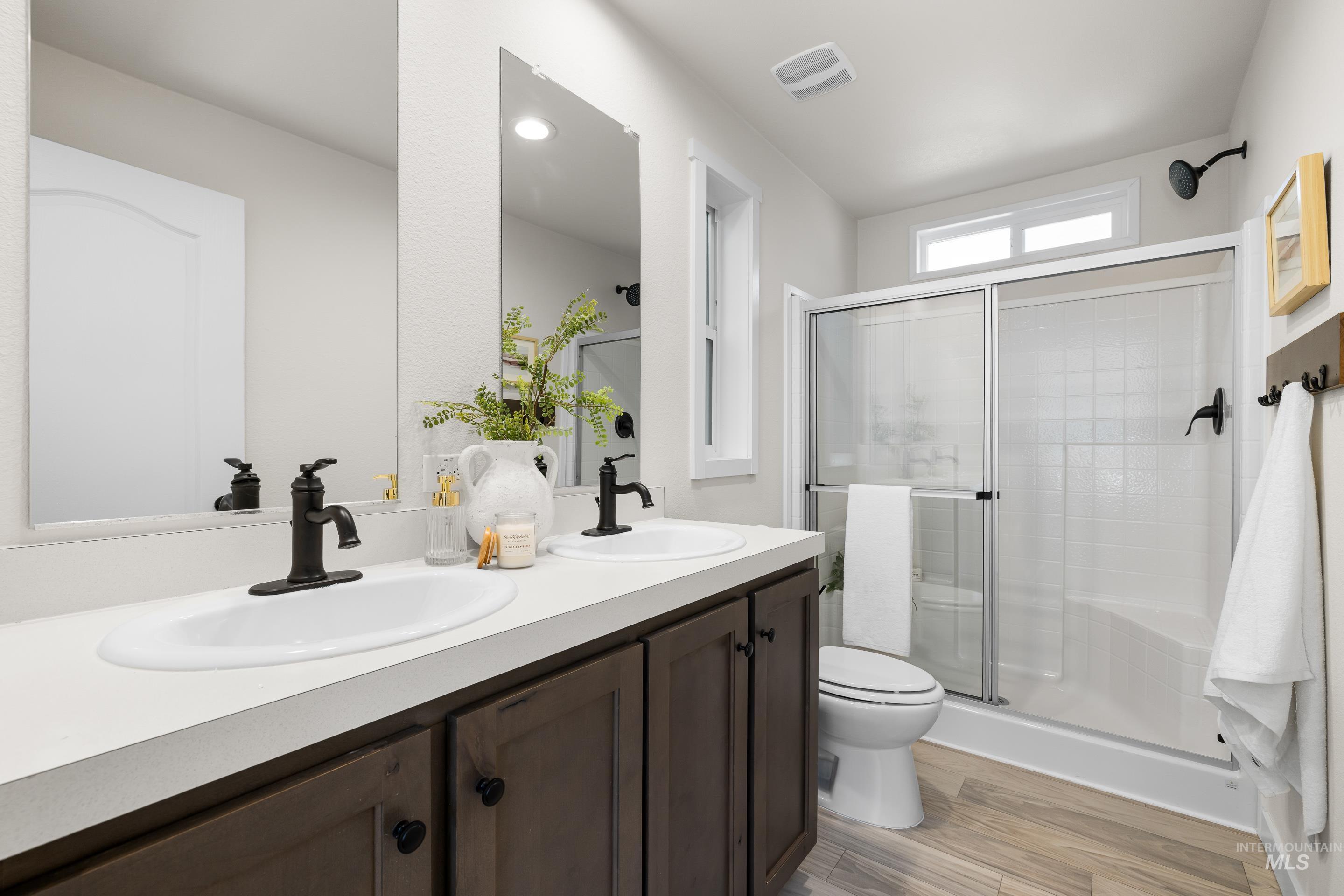 Bathroom featuring a stall shower, light wood finished floors, and double vanity