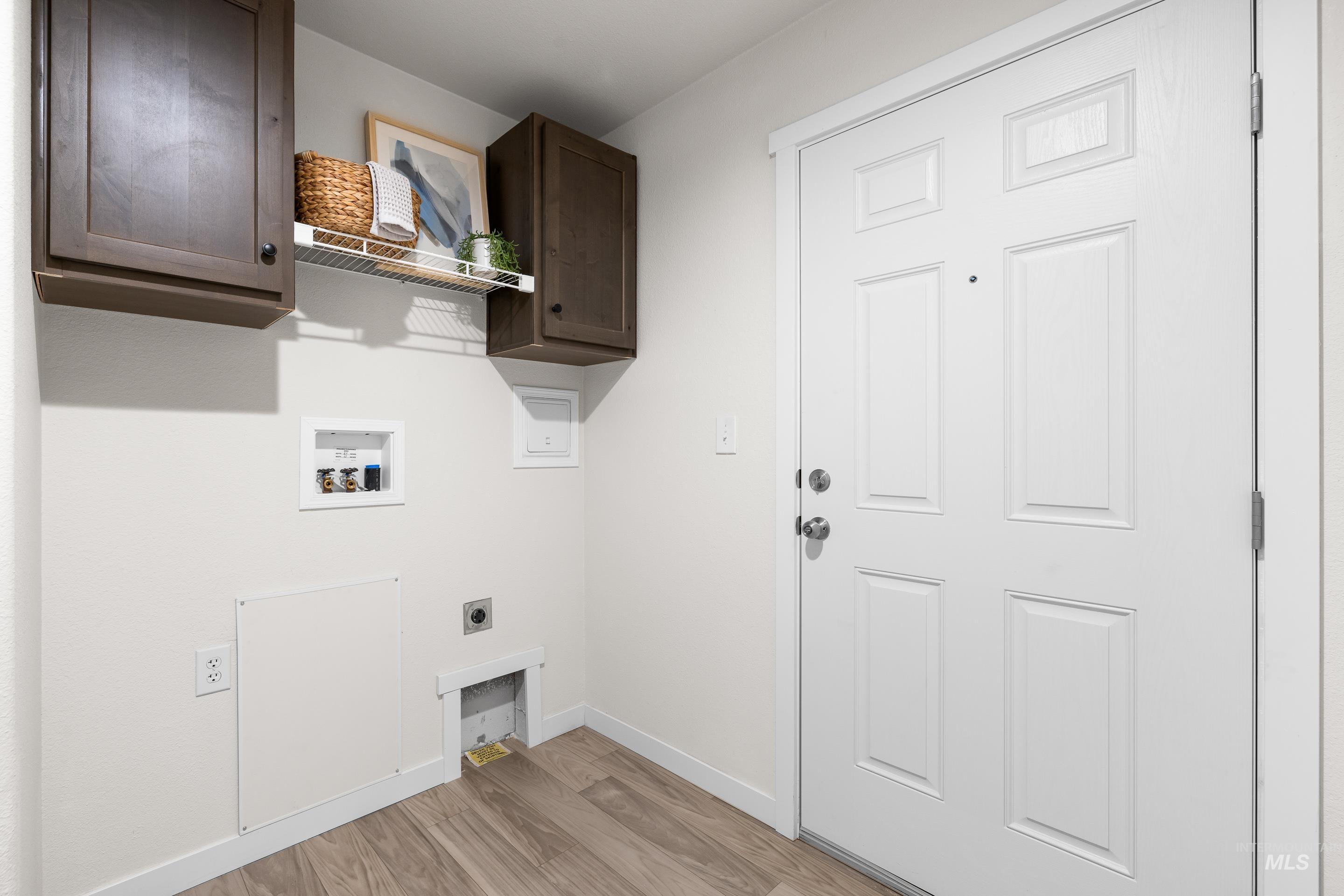 Laundry room with washer hookup, light wood-type flooring, hookup for an electric dryer, and cabinet space