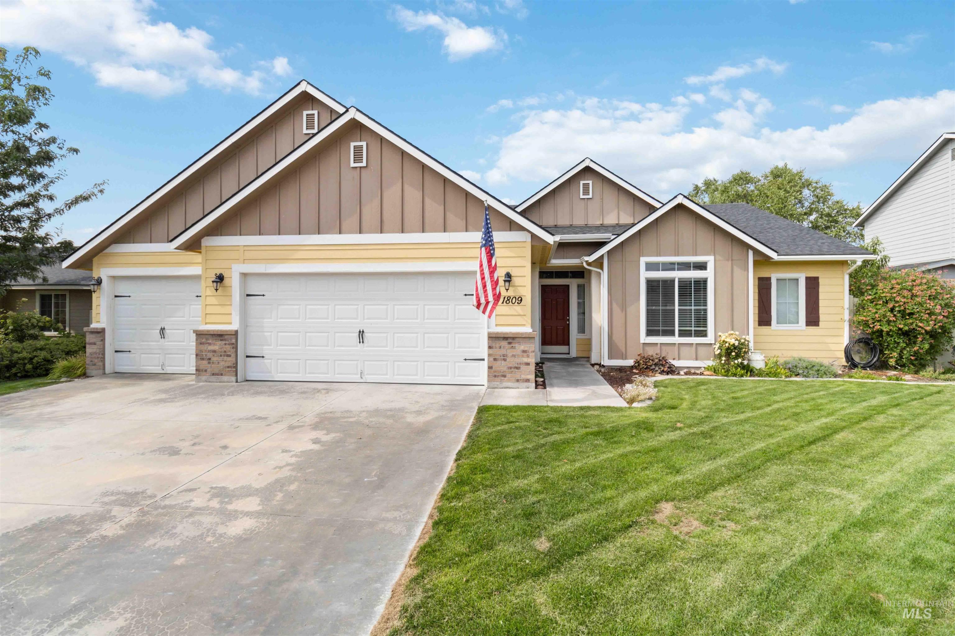 Craftsman house with board and batten siding, a garage, driveway, and a front yard