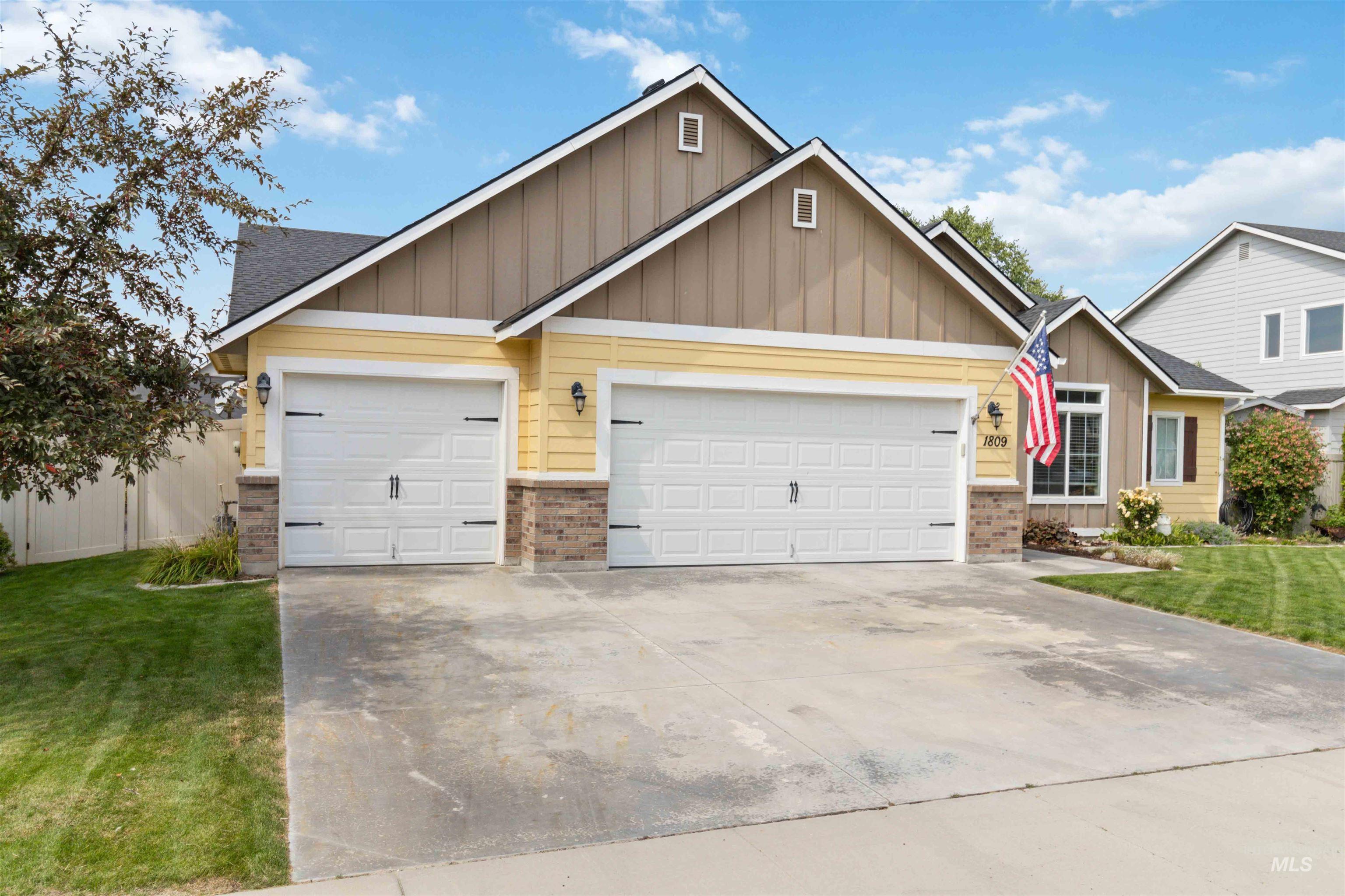 View of front of home featuring board and batten siding, driveway, an attached garage, and brick siding