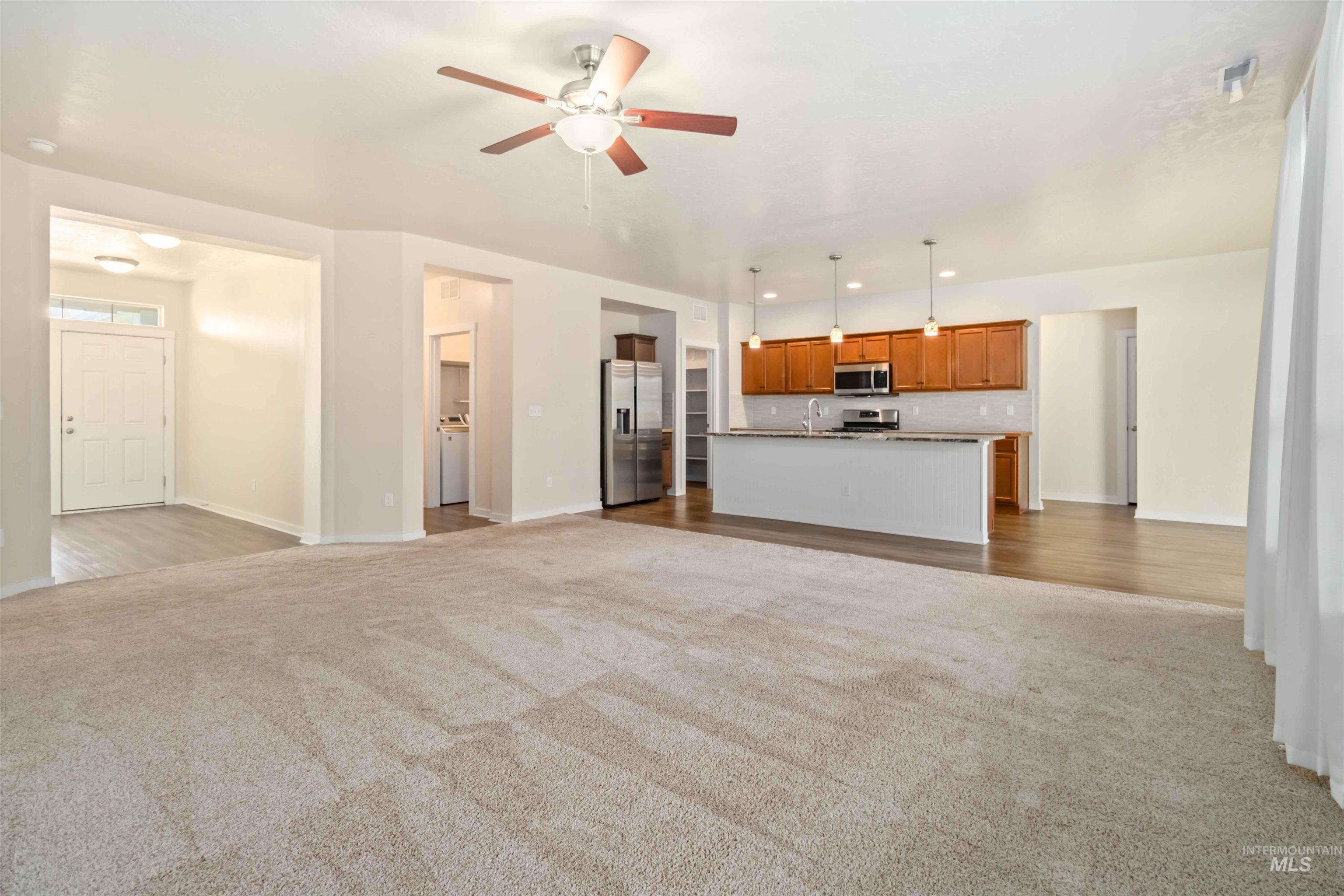 Unfurnished living room featuring dark colored carpet, a ceiling fan, recessed lighting, and washer / dryer