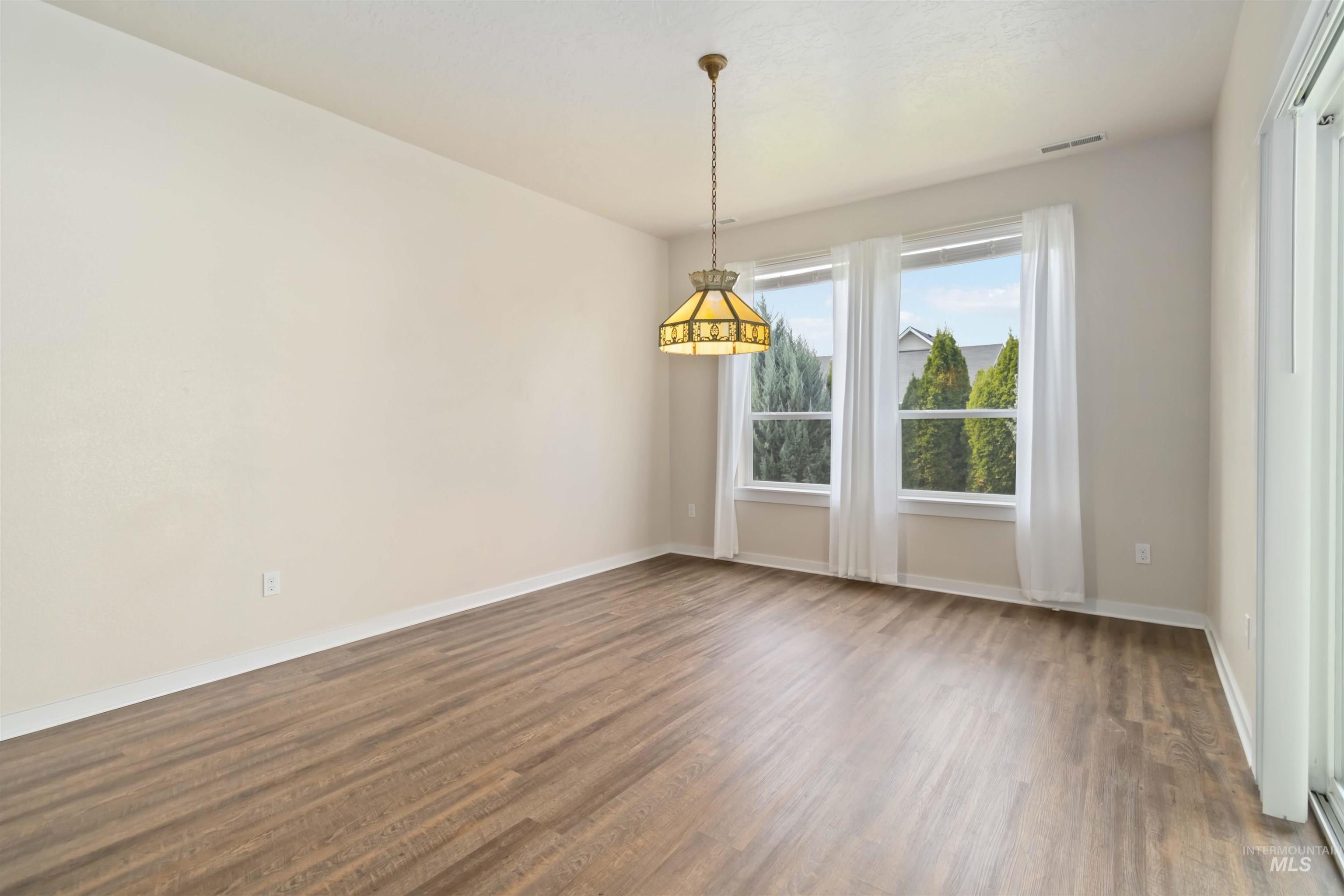Spare room with baseboards and dark wood-style floors