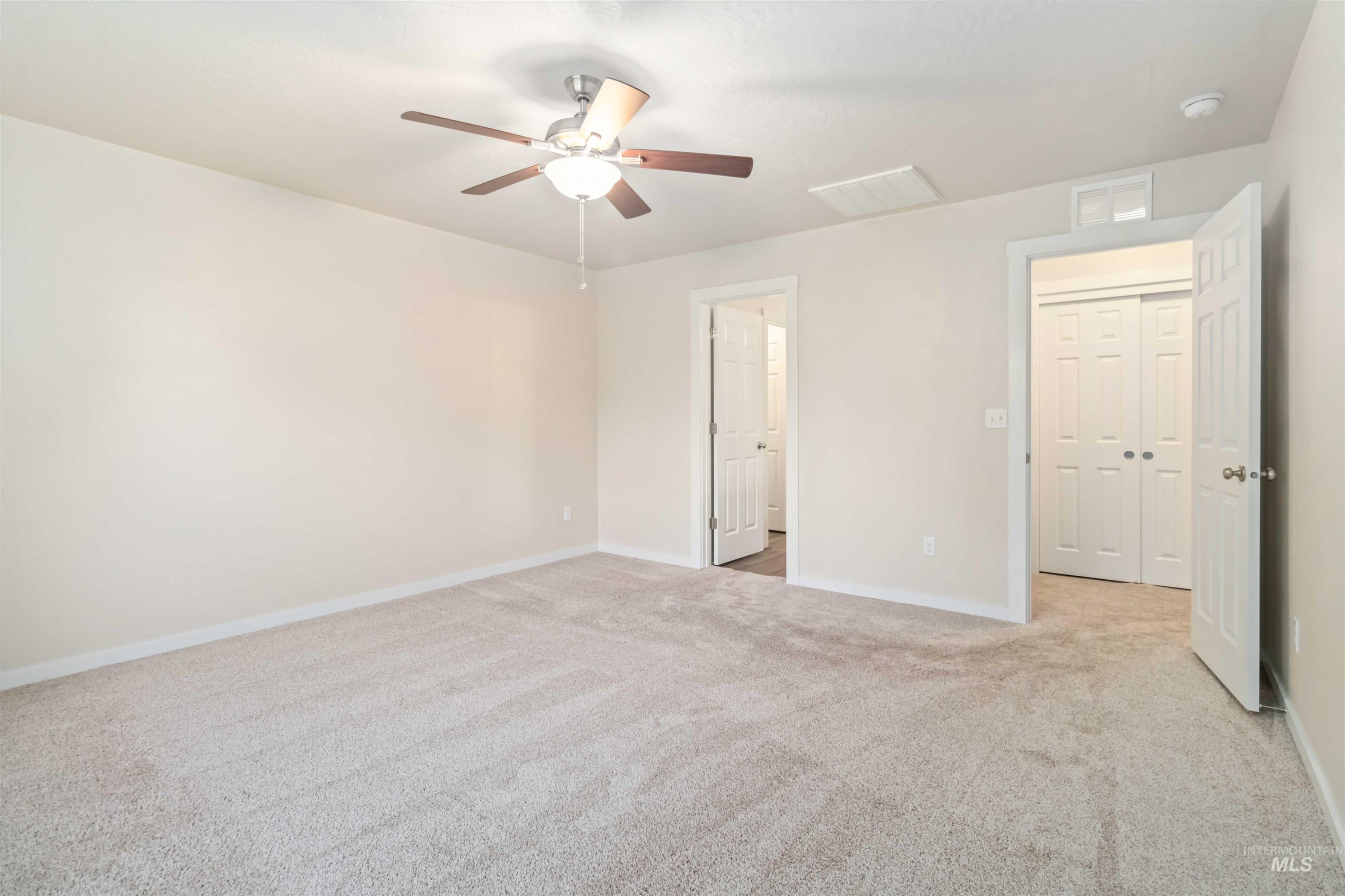 Unfurnished bedroom with light colored carpet and a ceiling fan