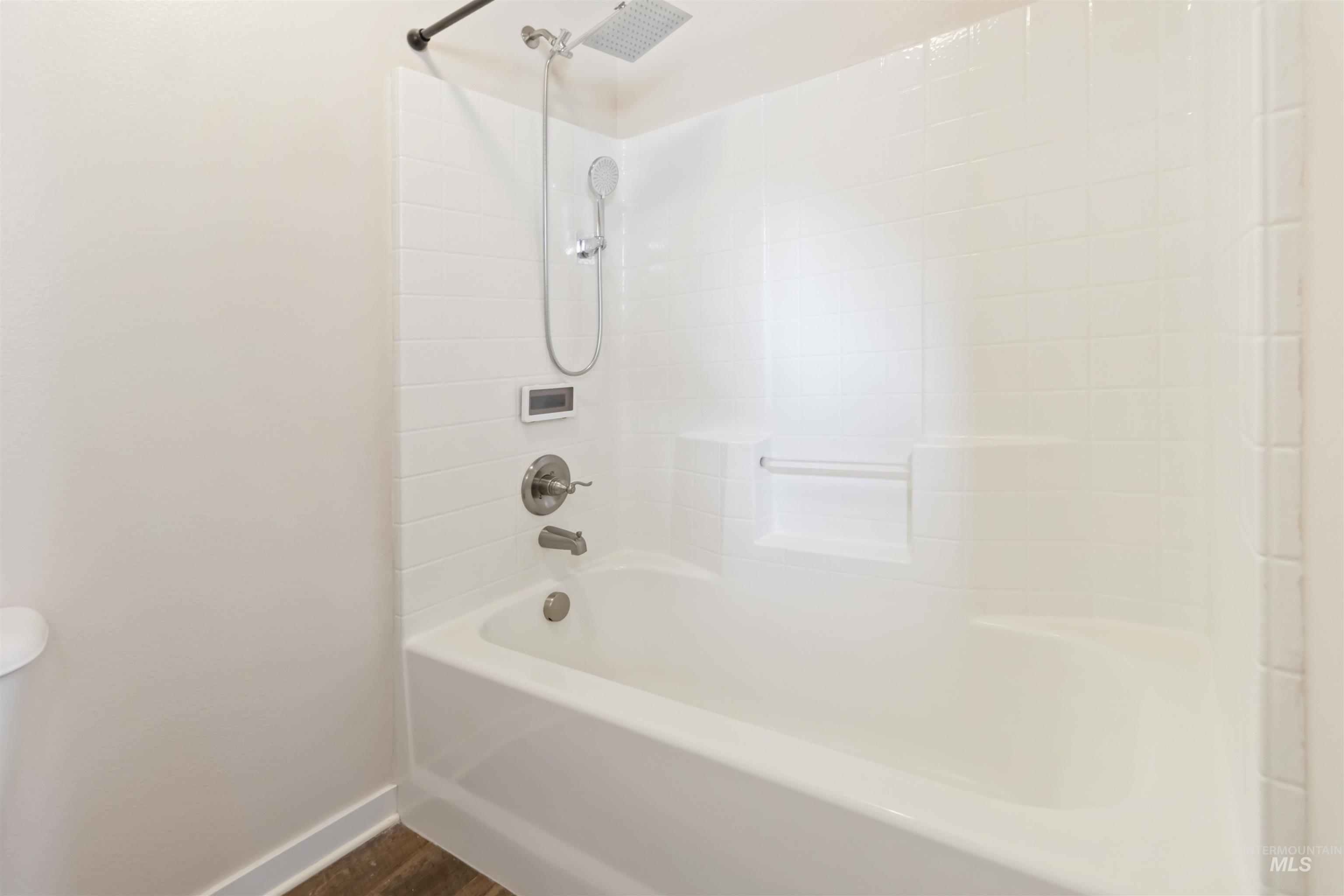 Bathroom featuring bathing tub / shower combination and dark wood-style floors