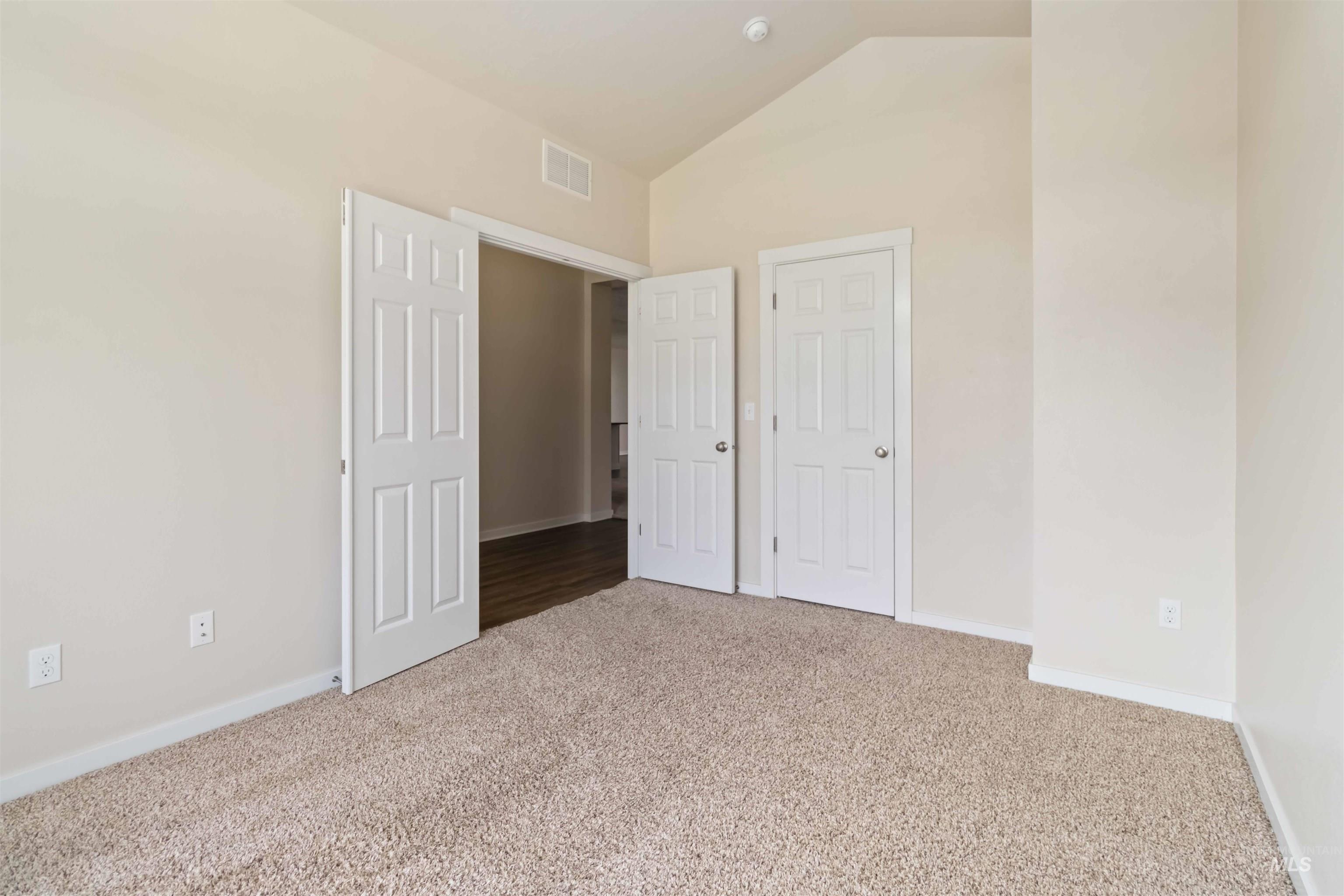 Unfurnished bedroom with light colored carpet and high vaulted ceiling