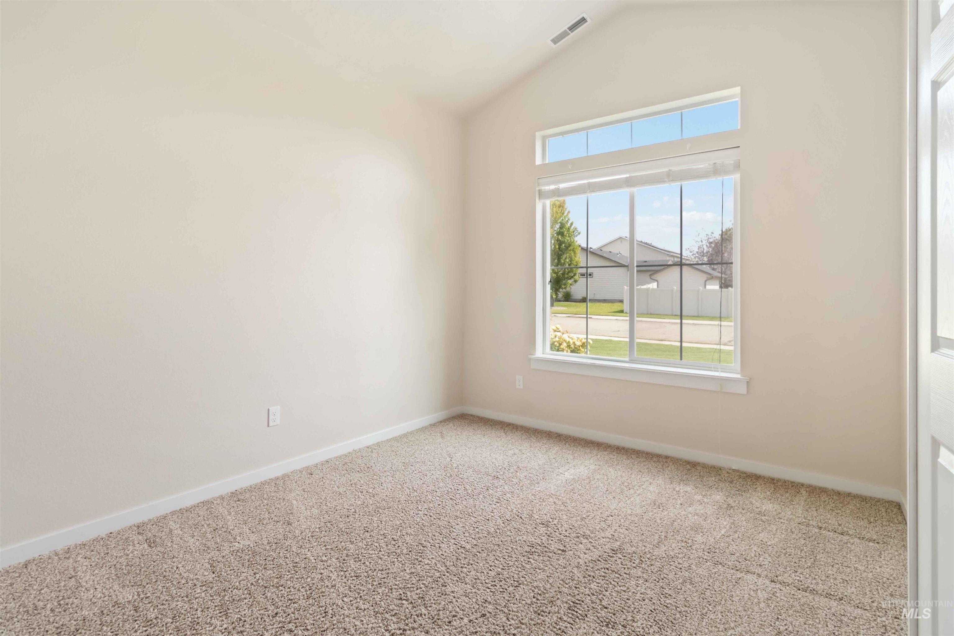 Empty room featuring carpet flooring and vaulted ceiling
