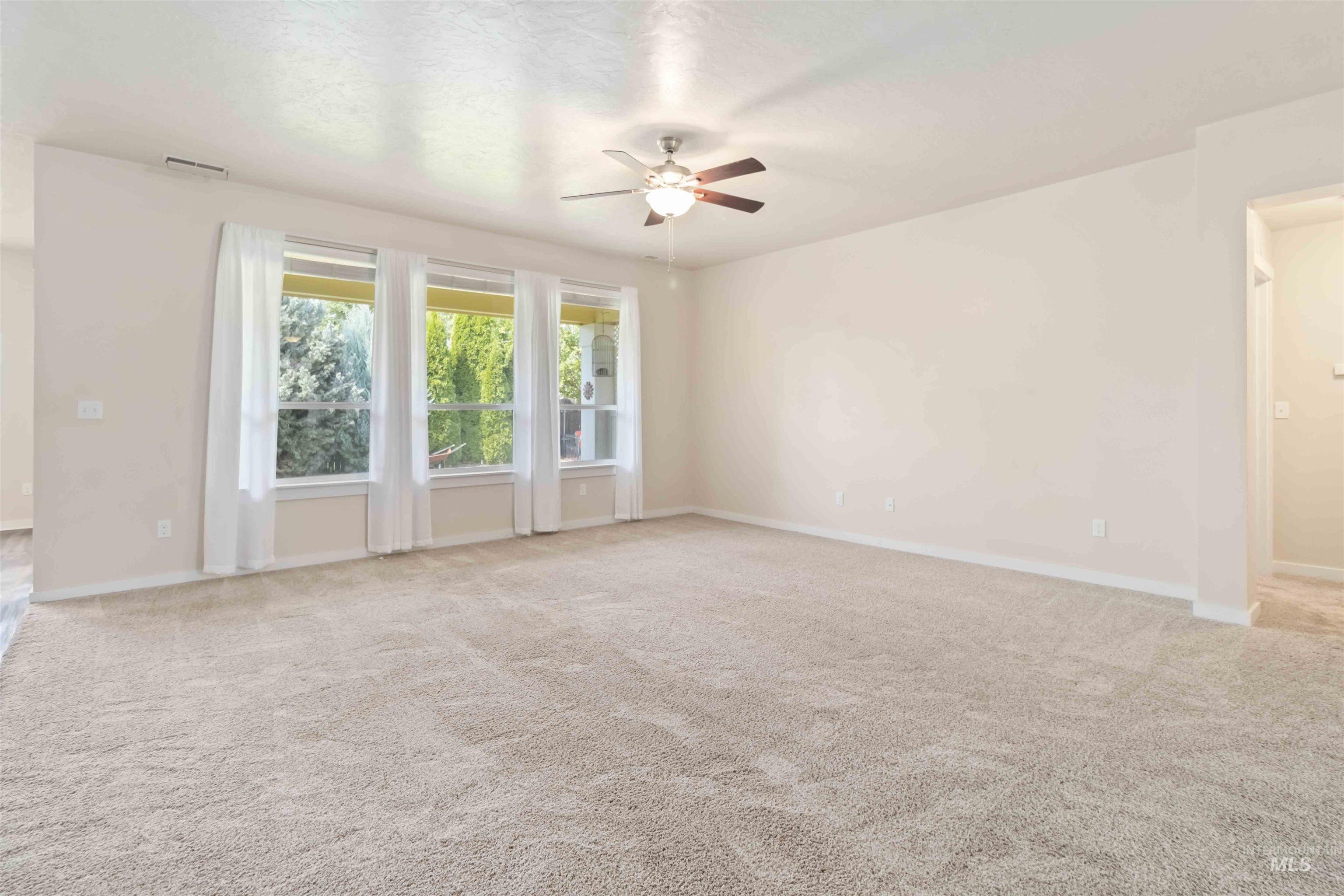 Unfurnished room with light colored carpet and a ceiling fan