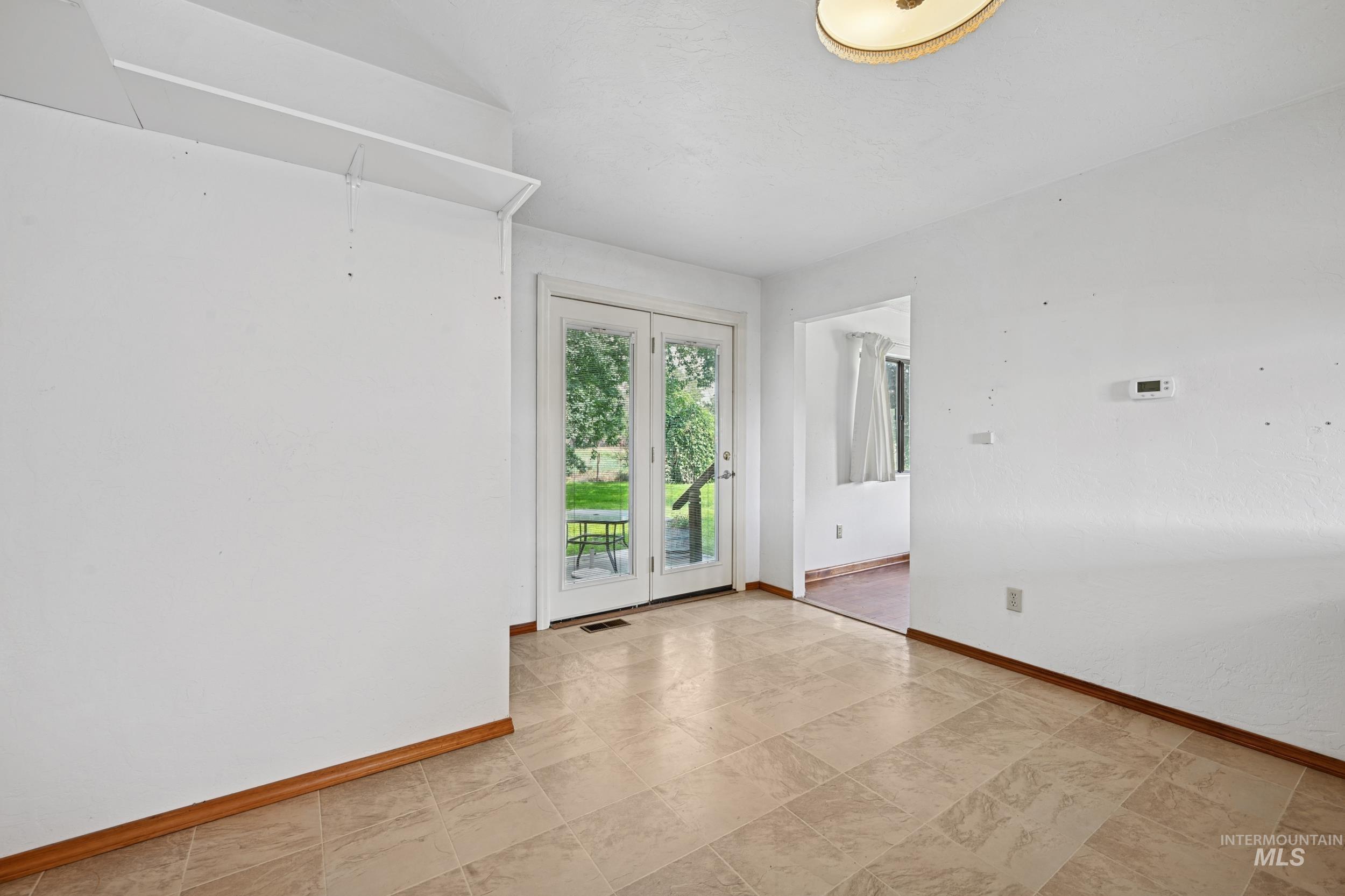 Unfurnished room featuring baseboards and attic access