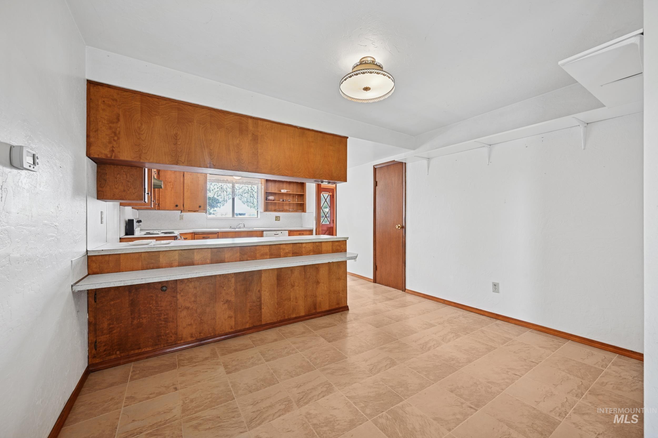 Kitchen featuring brown cabinets, light countertops, open shelves, a peninsula, and white range with electric cooktop