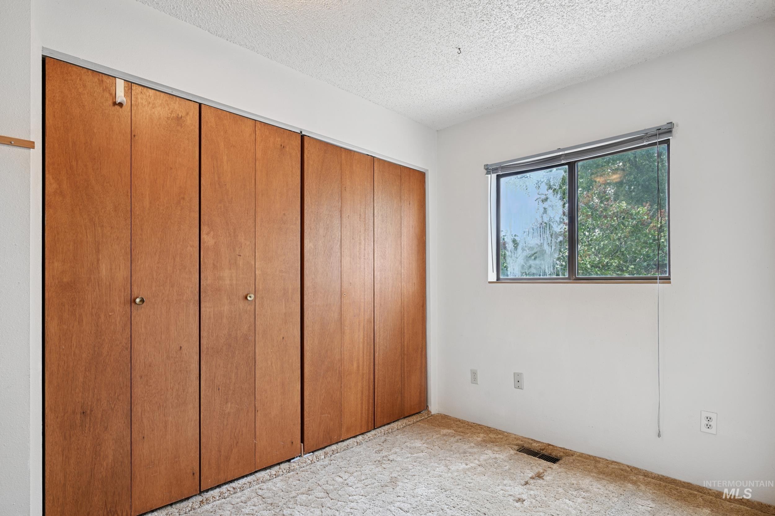 Unfurnished bedroom featuring a textured ceiling, a closet, and carpet flooring