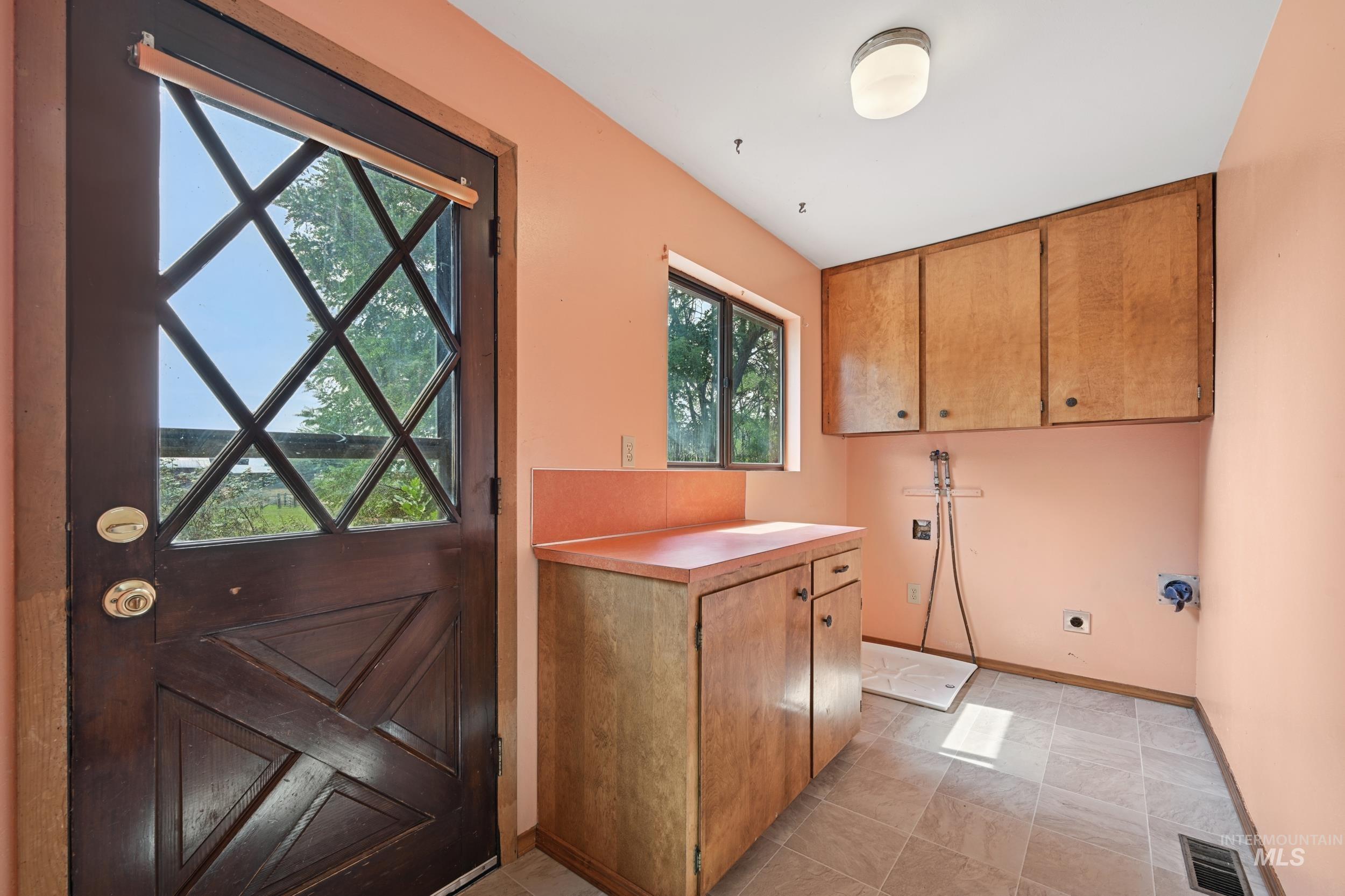 Laundry area with electric dryer hookup, washer hookup, cabinet space, and light tile patterned floors