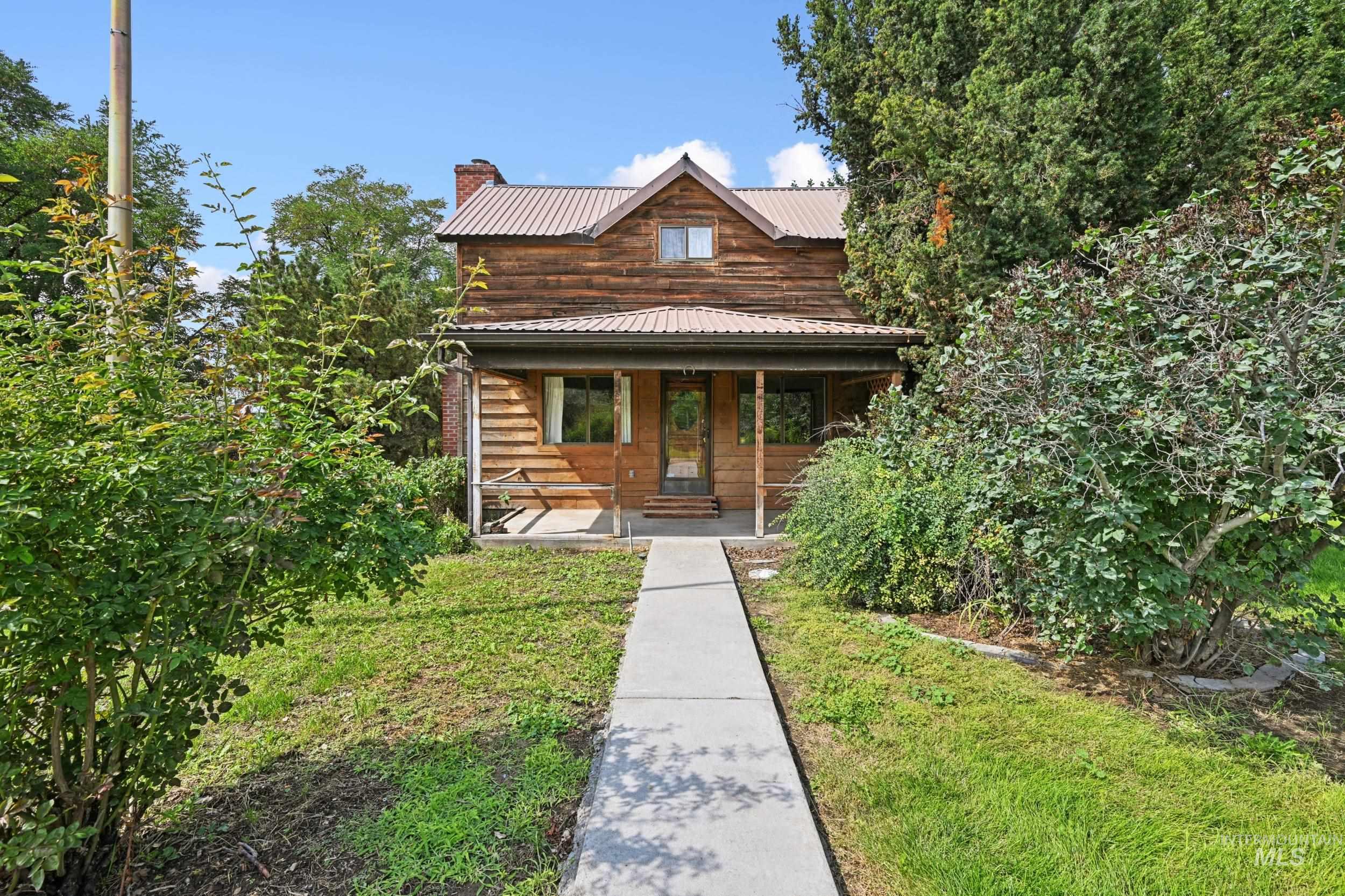View of front of home featuring covered porch, a chimney, a metal roof, and a front yard