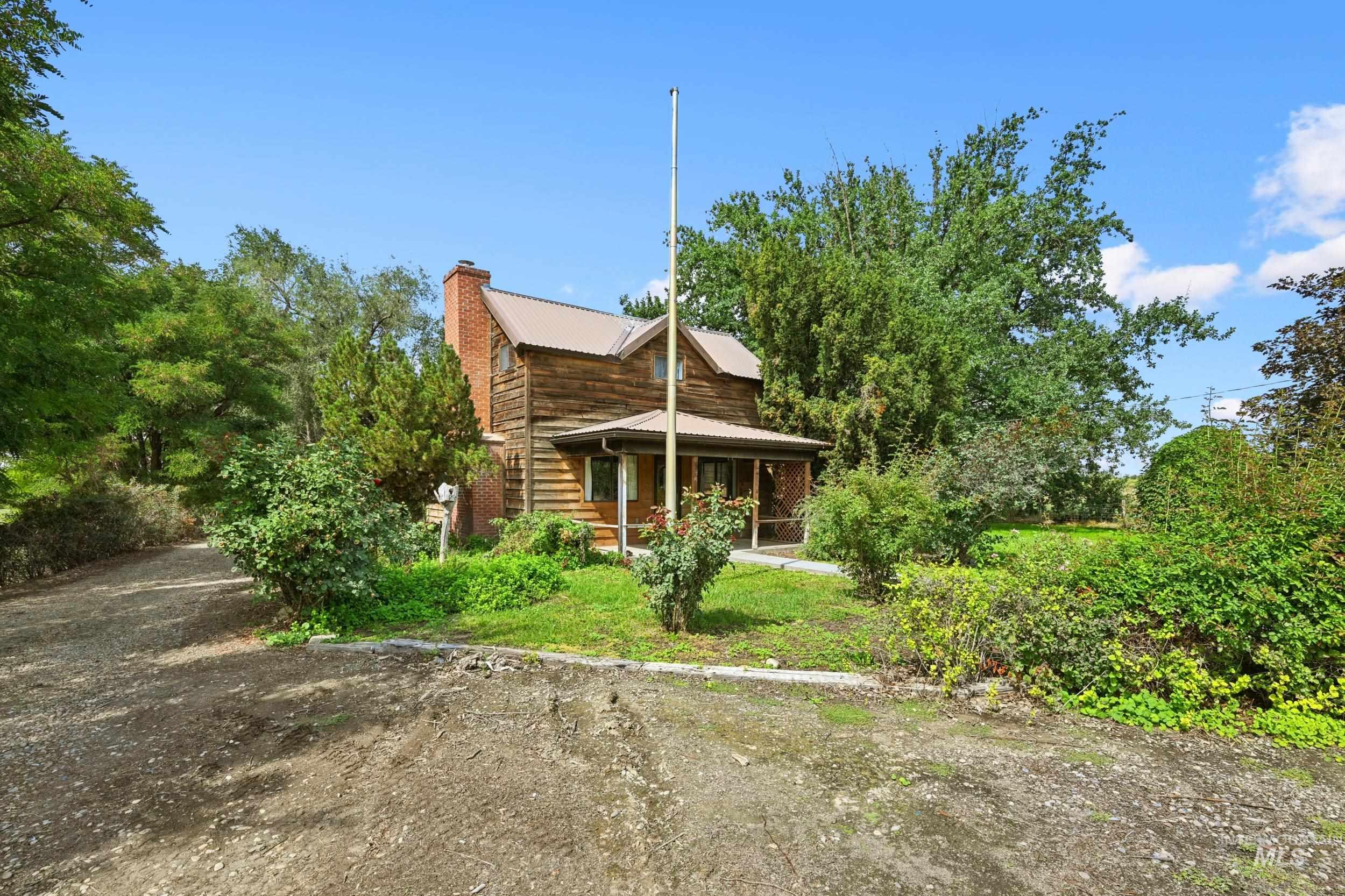 Rear view of property featuring a chimney, a metal roof, and covered porch
