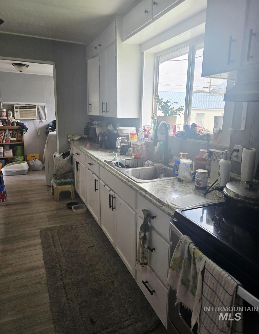 Kitchen featuring range with electric stovetop, light countertops, white cabinets, dark wood-type flooring, and washer / dryer