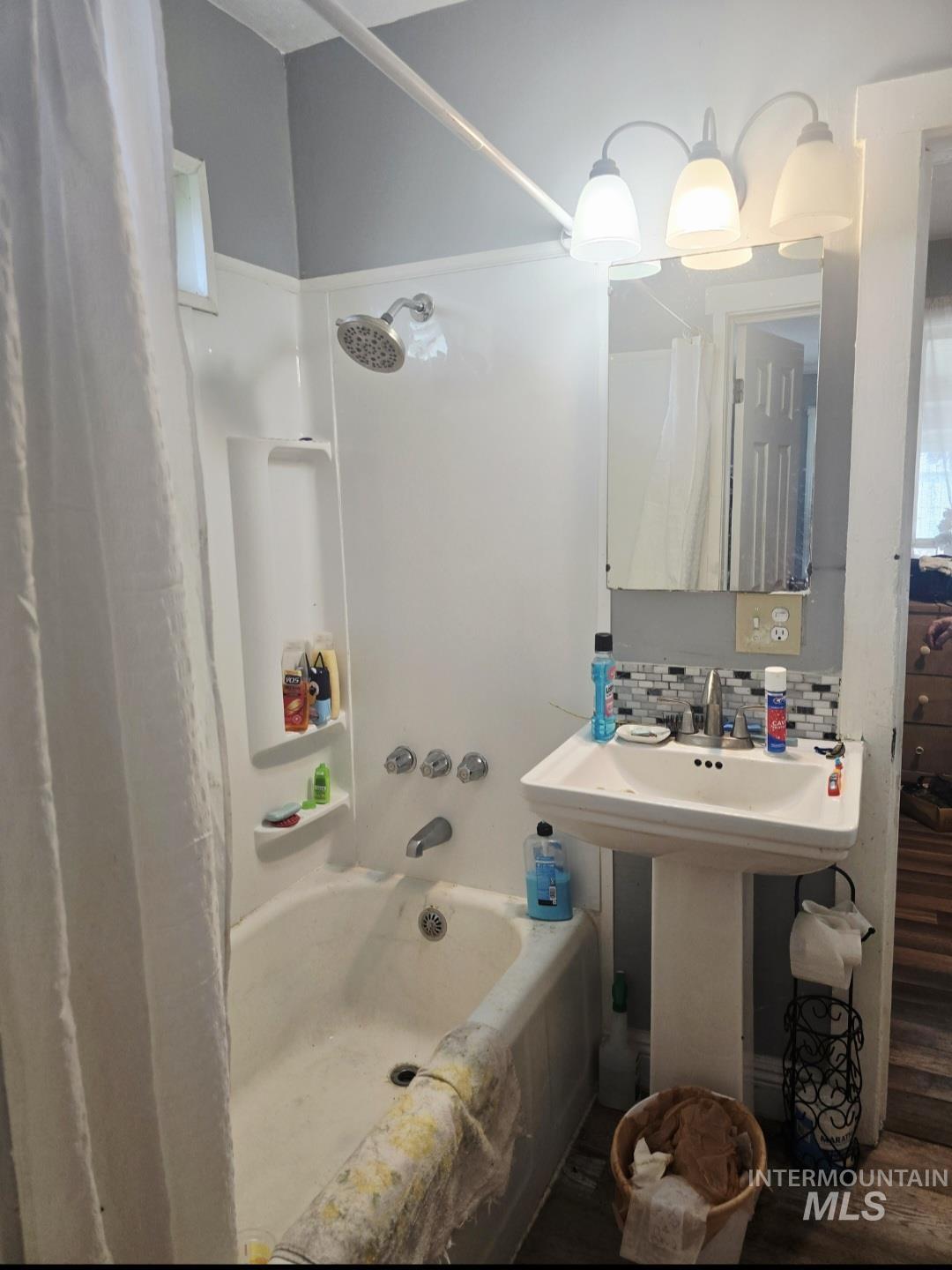 Full bathroom featuring shower / bath combination with curtain, decorative backsplash, and wood finished floors