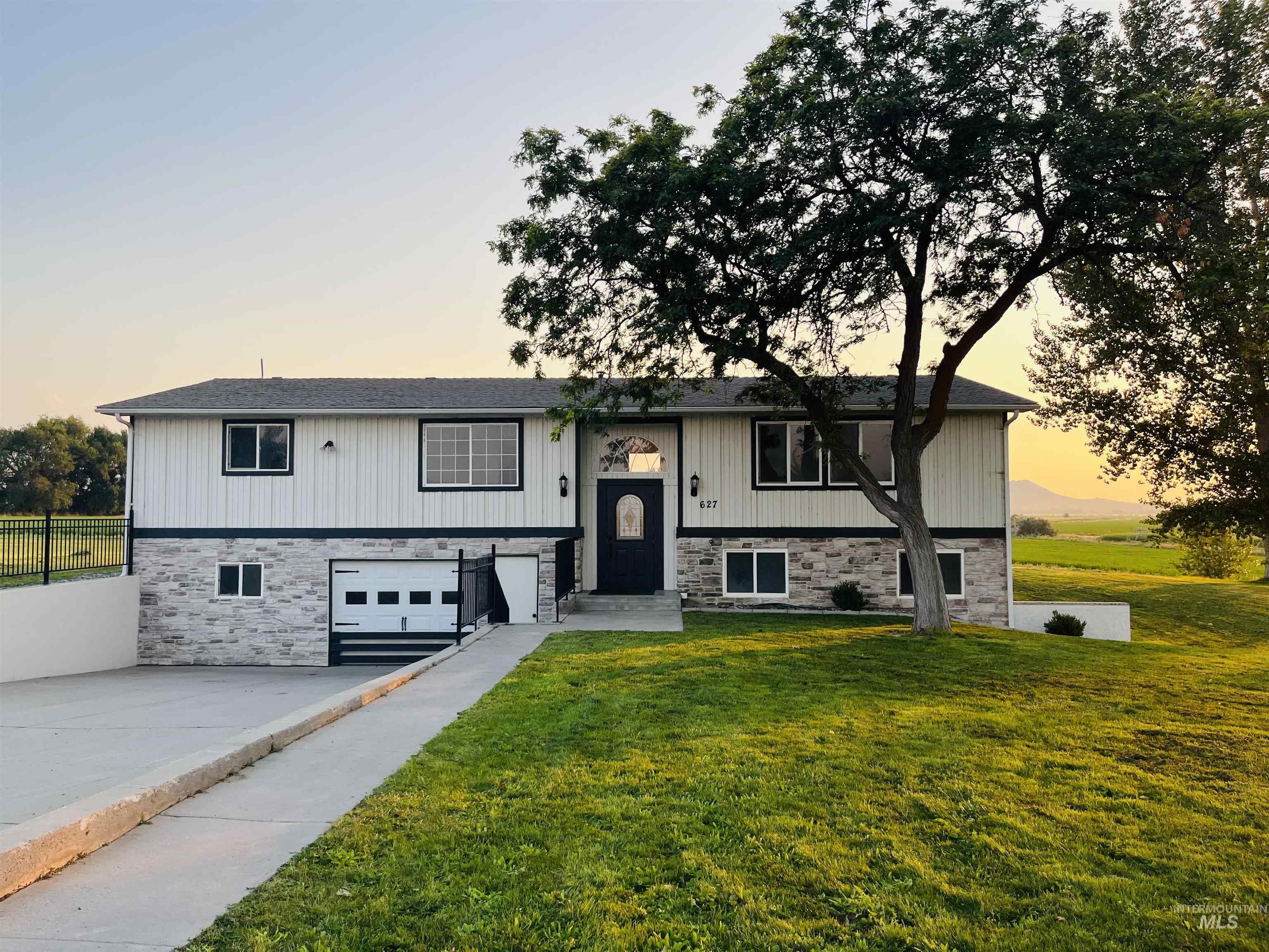 Split foyer home featuring concrete driveway, stone siding, a garage, and a front yard