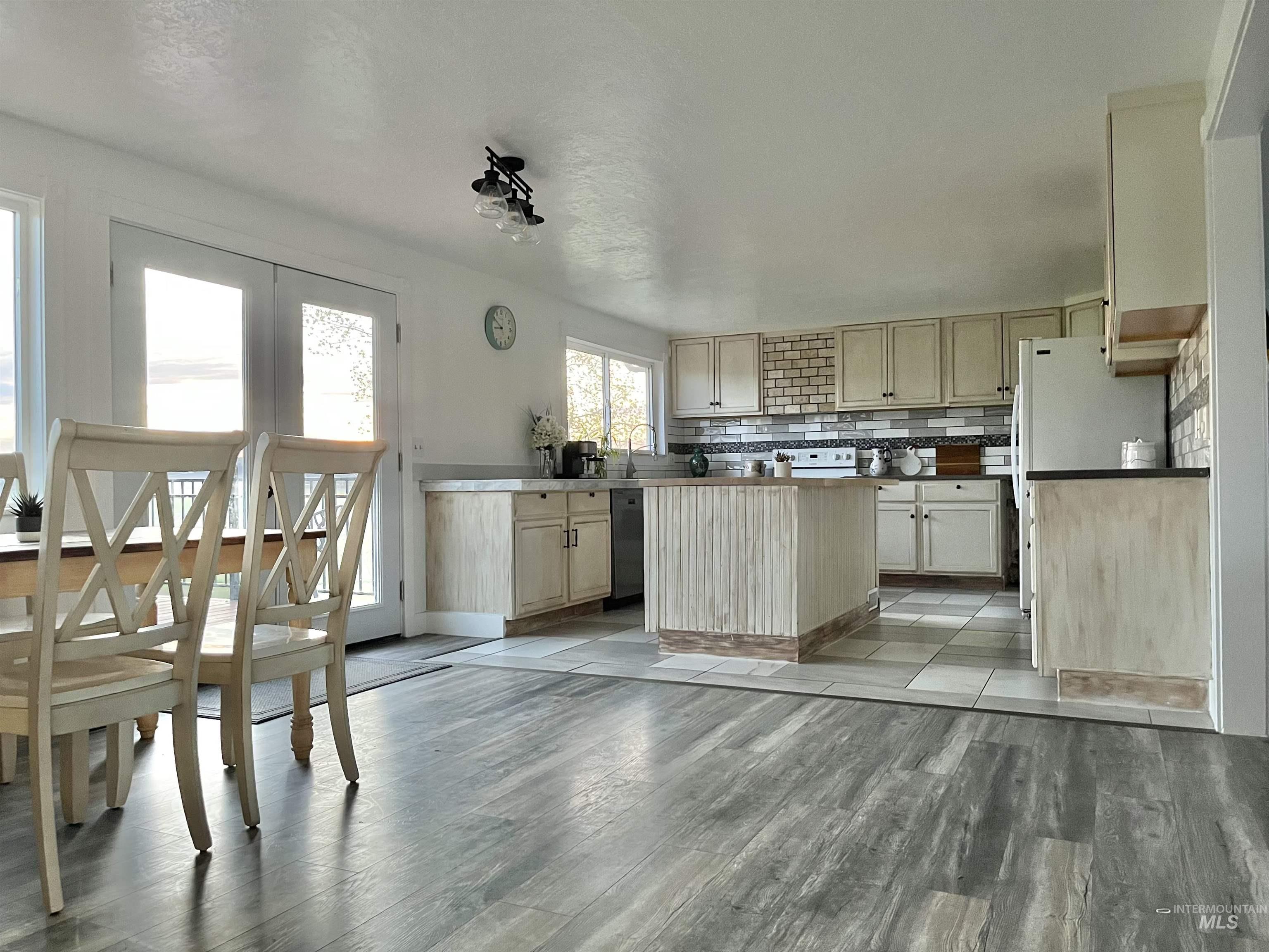 Kitchen with light brown cabinetry, decorative backsplash, a center island, white appliances, and light wood-style flooring