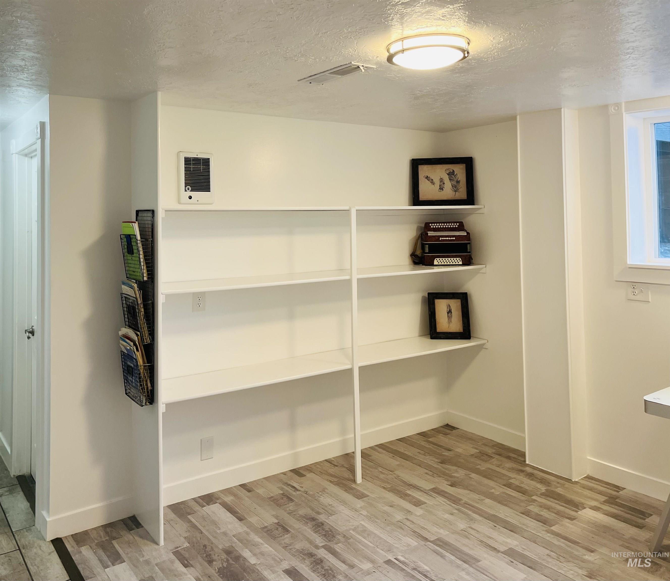 Unfurnished office featuring a textured ceiling and light wood-type flooring