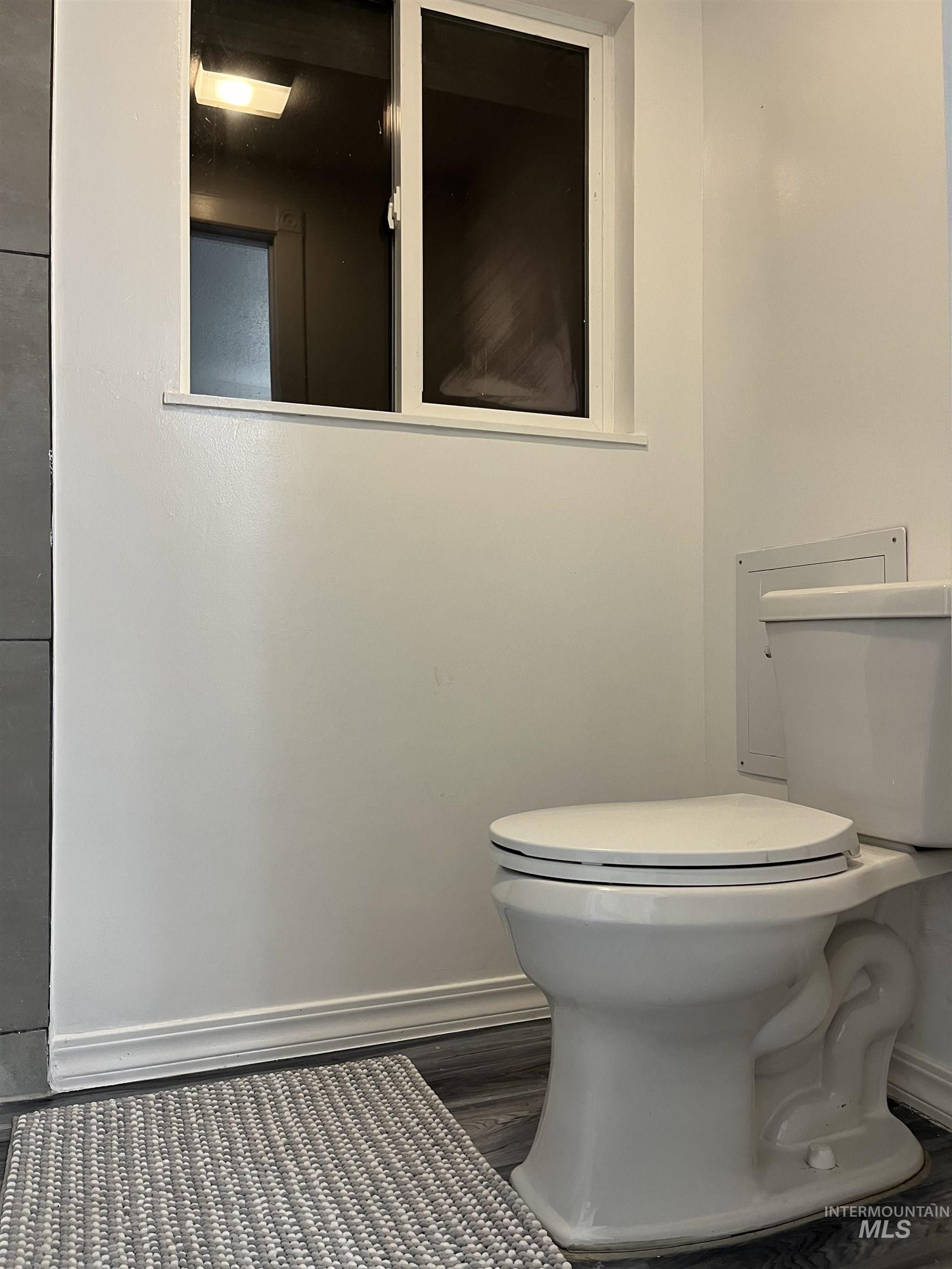 Half bath featuring baseboards and dark wood-type flooring