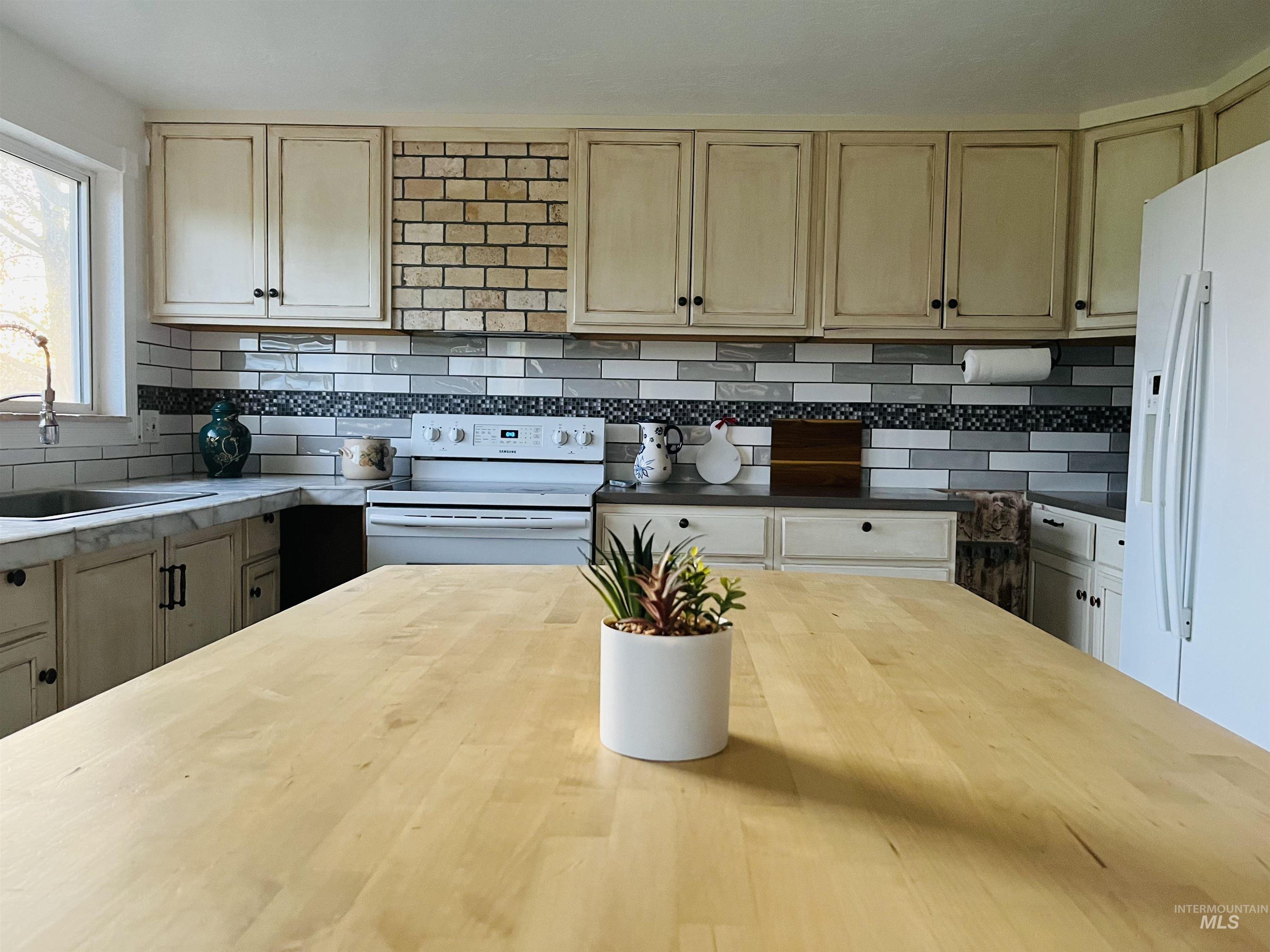 Kitchen featuring backsplash and white appliances