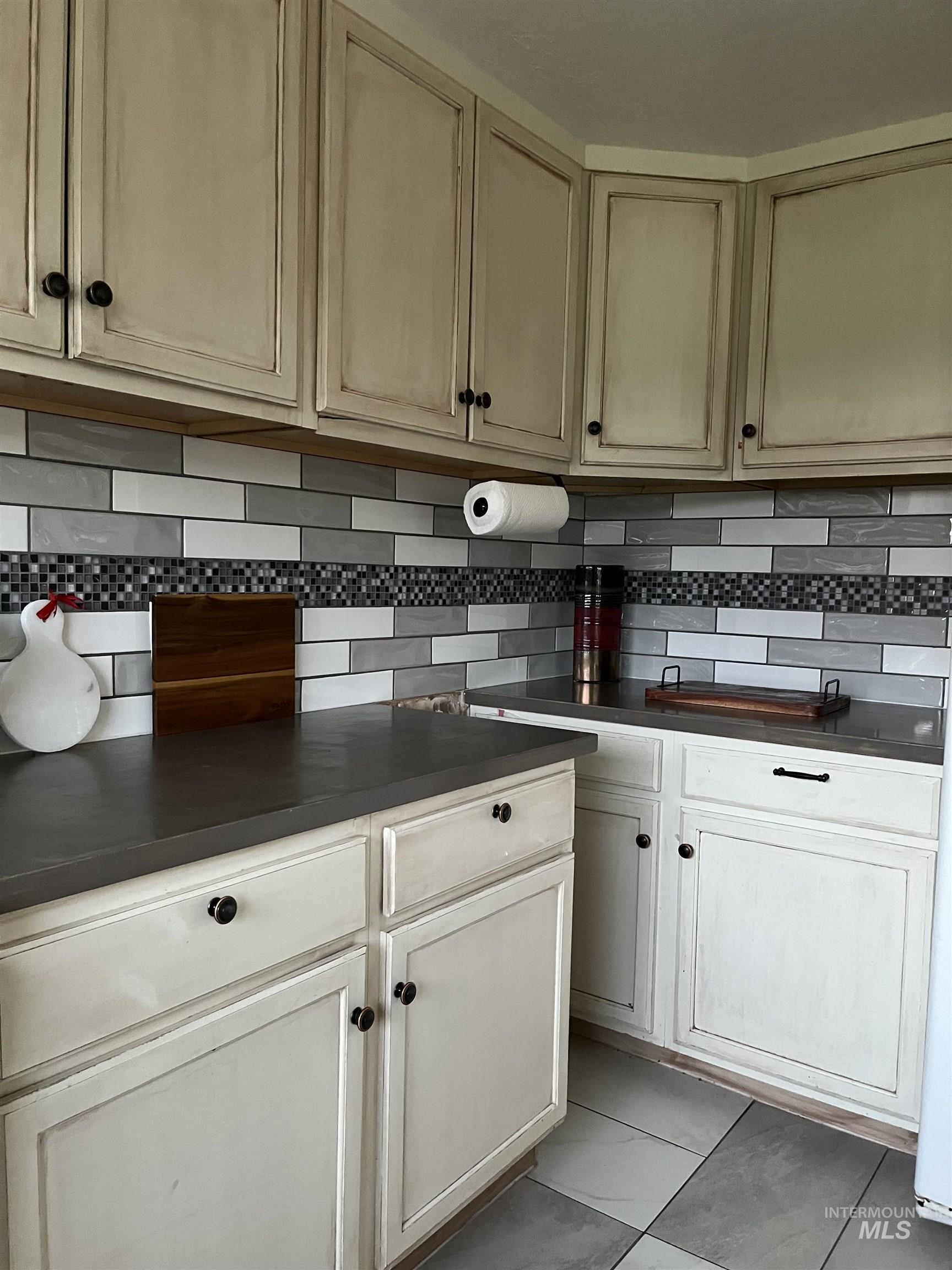 Kitchen featuring dark countertops, tasteful backsplash, and light tile patterned flooring