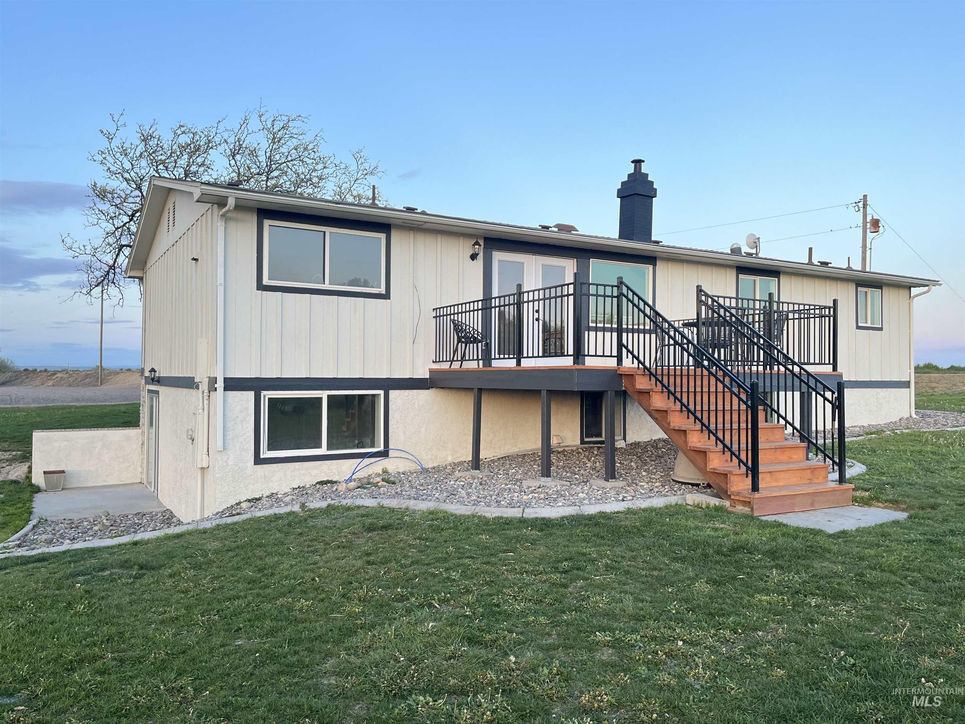 Back of house featuring stairway, a wooden deck, a chimney, and a yard