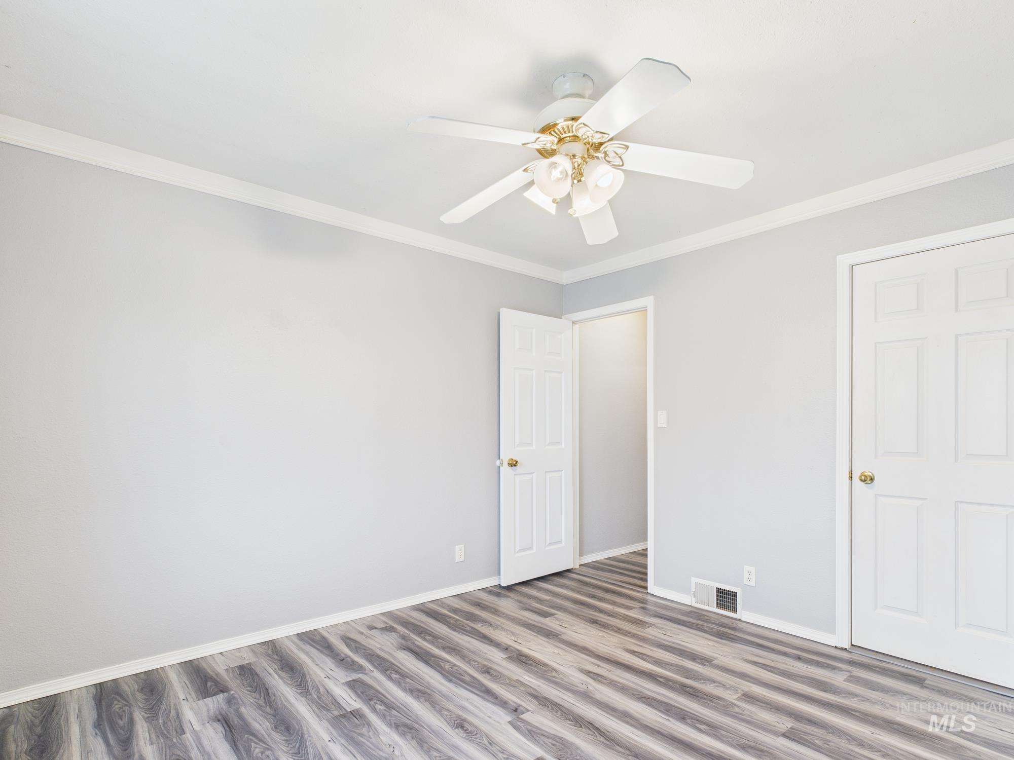 Unfurnished bedroom with ornamental molding, wood finished floors, and ceiling fan