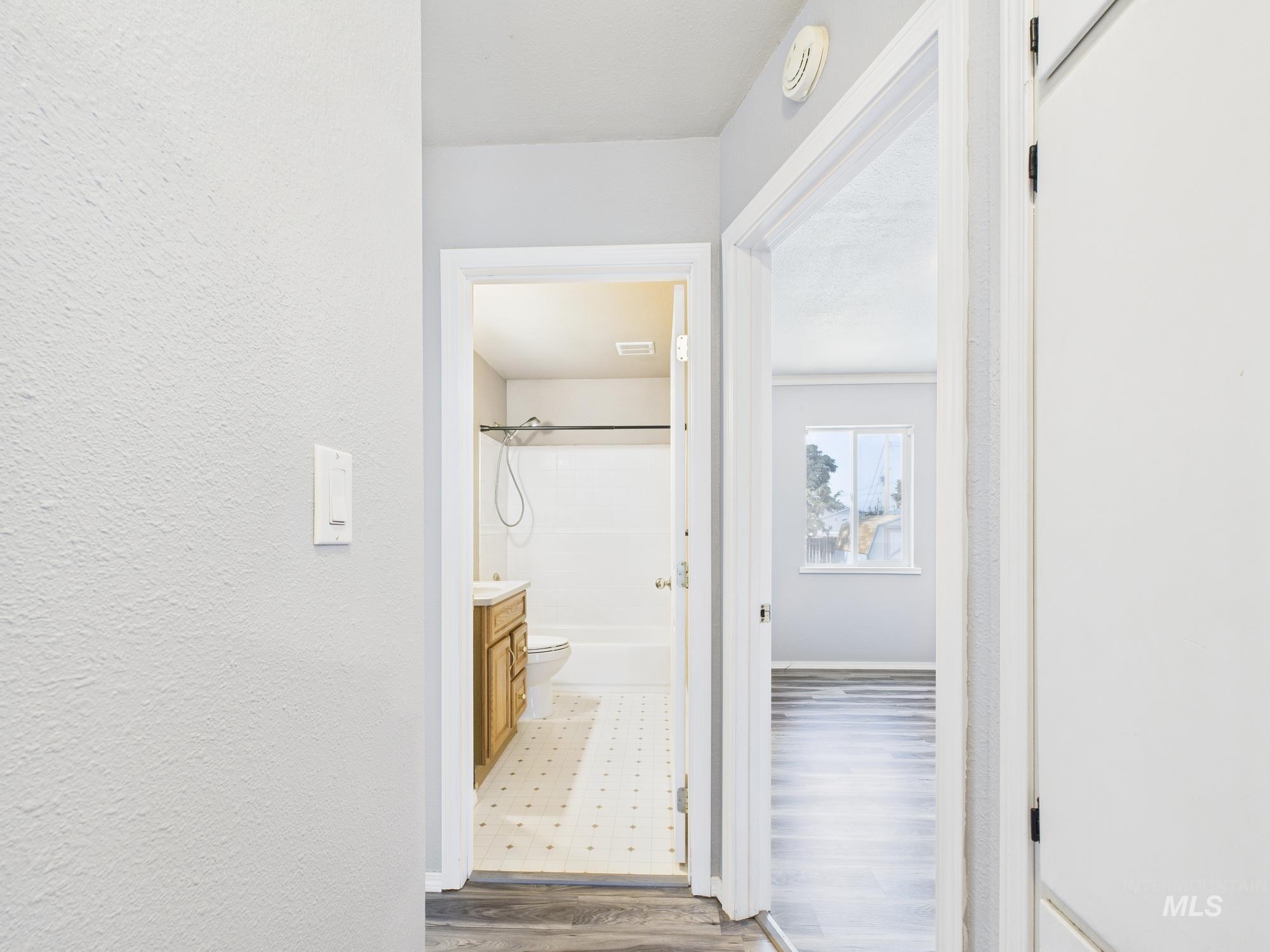 Hall featuring dark wood-style flooring and a textured wall