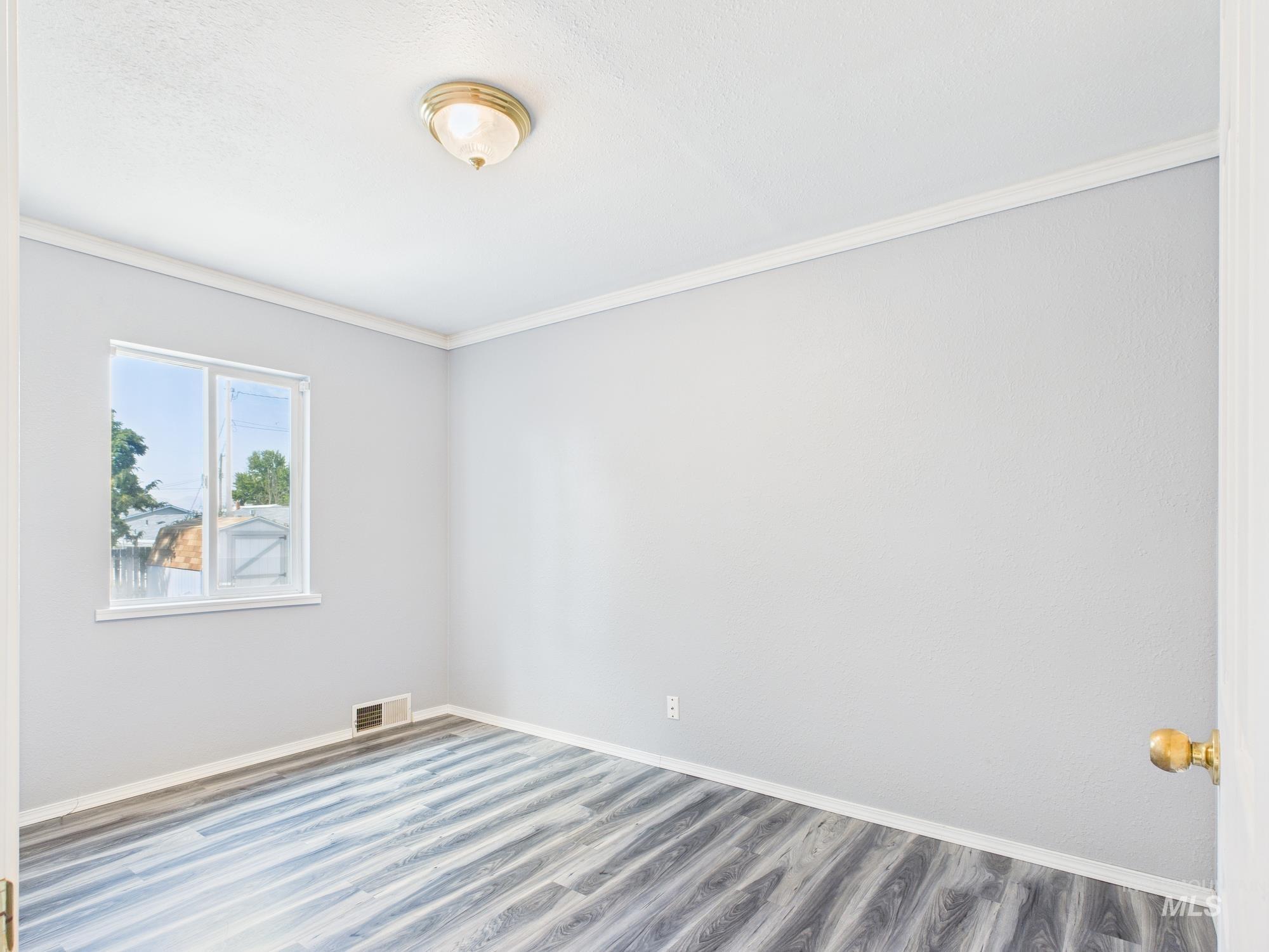 Empty room with crown molding and wood finished floors